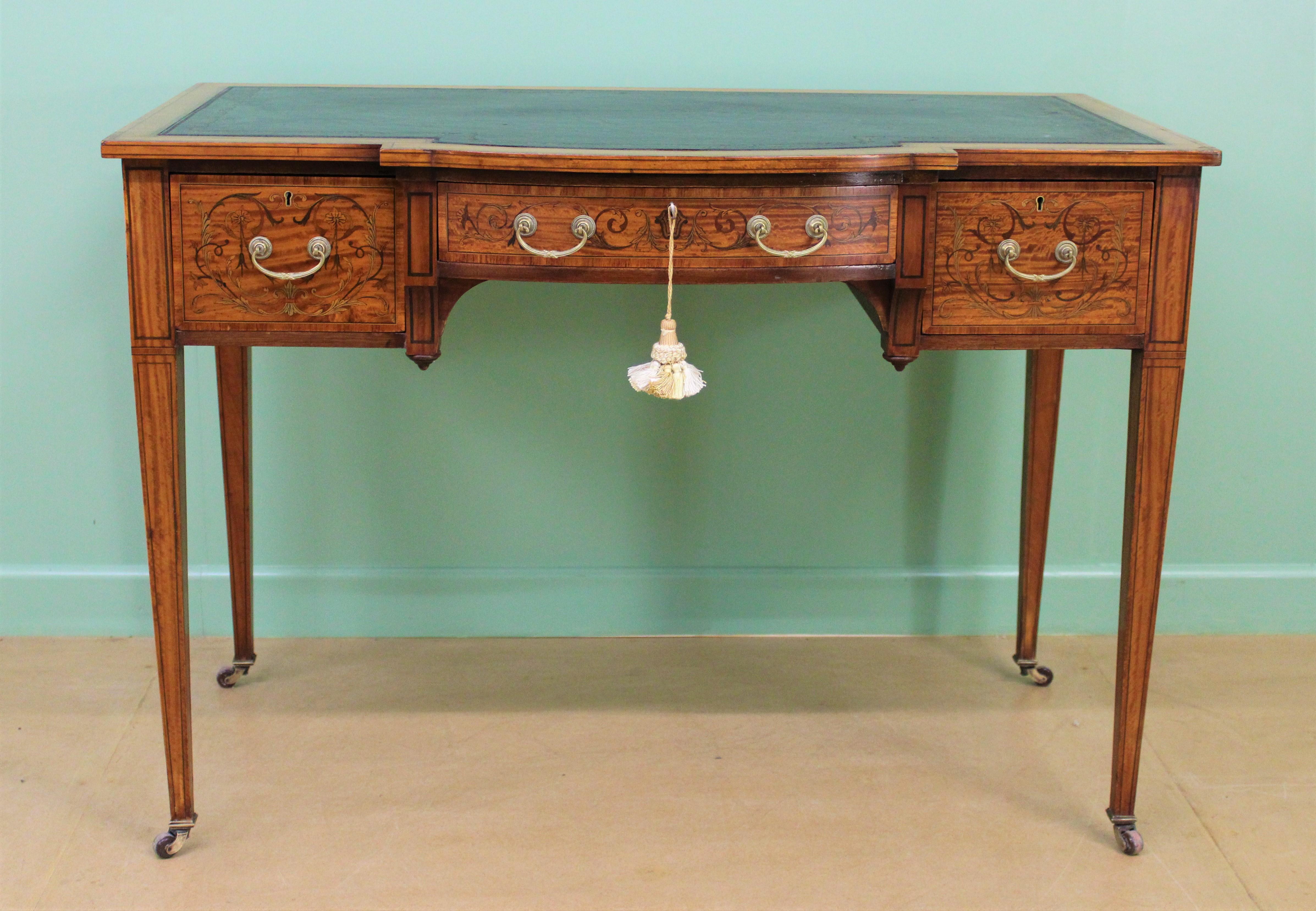 A fine quality inlaid satinwood writing table by the prestigious firm of Maple and Co of London. Dating to the late Victorian period and very well made with stunning satinwood veneers onto a solid mahogany frame. The top and drawer fronts are