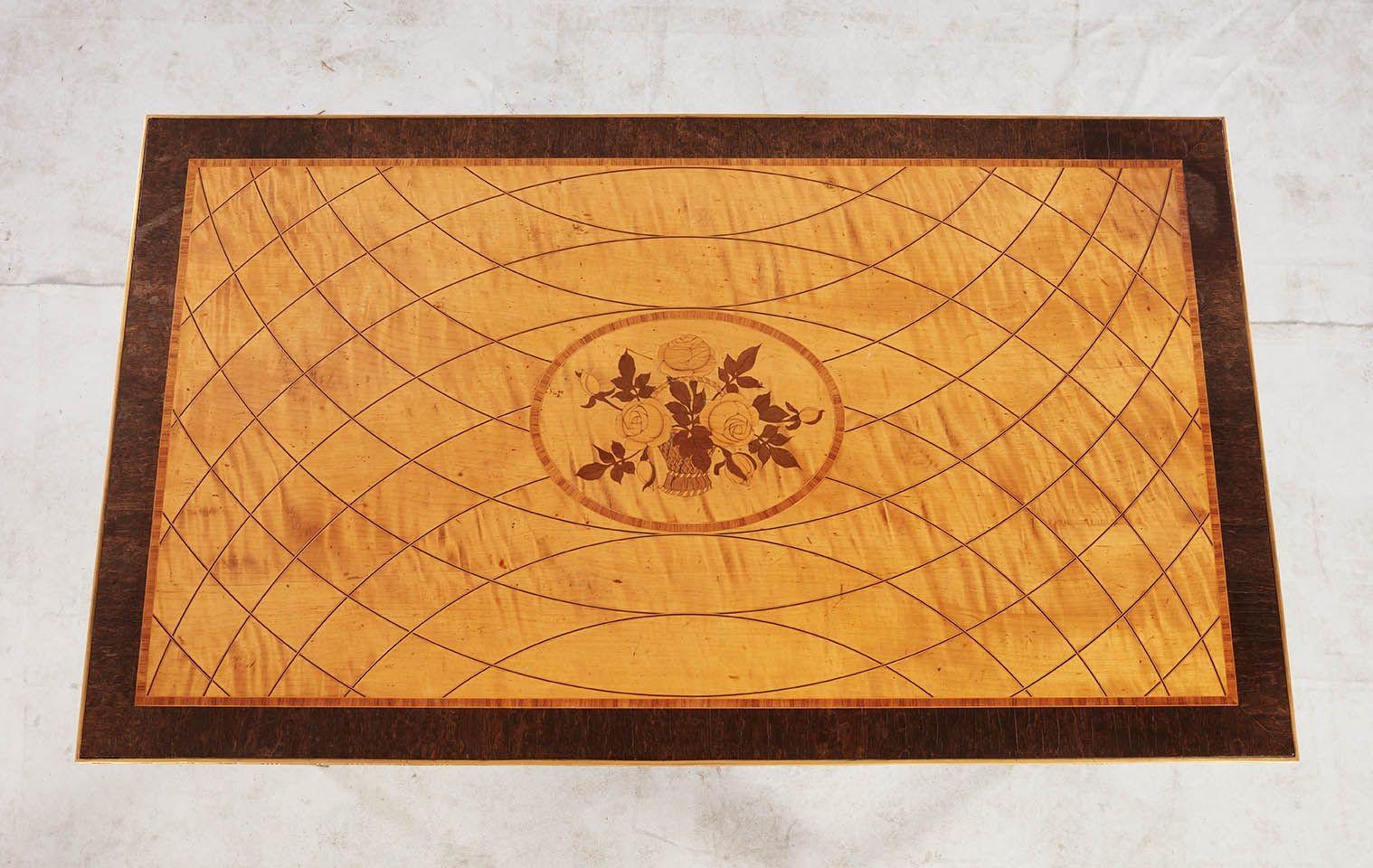 Raffinato tavolino da centro svedese del XIX secolo montato in bronzo dorato alla maniera di George Haupt. In legni misti, il piano con cesto di fiori intarsiato all'interno di un ovale su un fondo di betulla satinata con intarsio di corde a curva