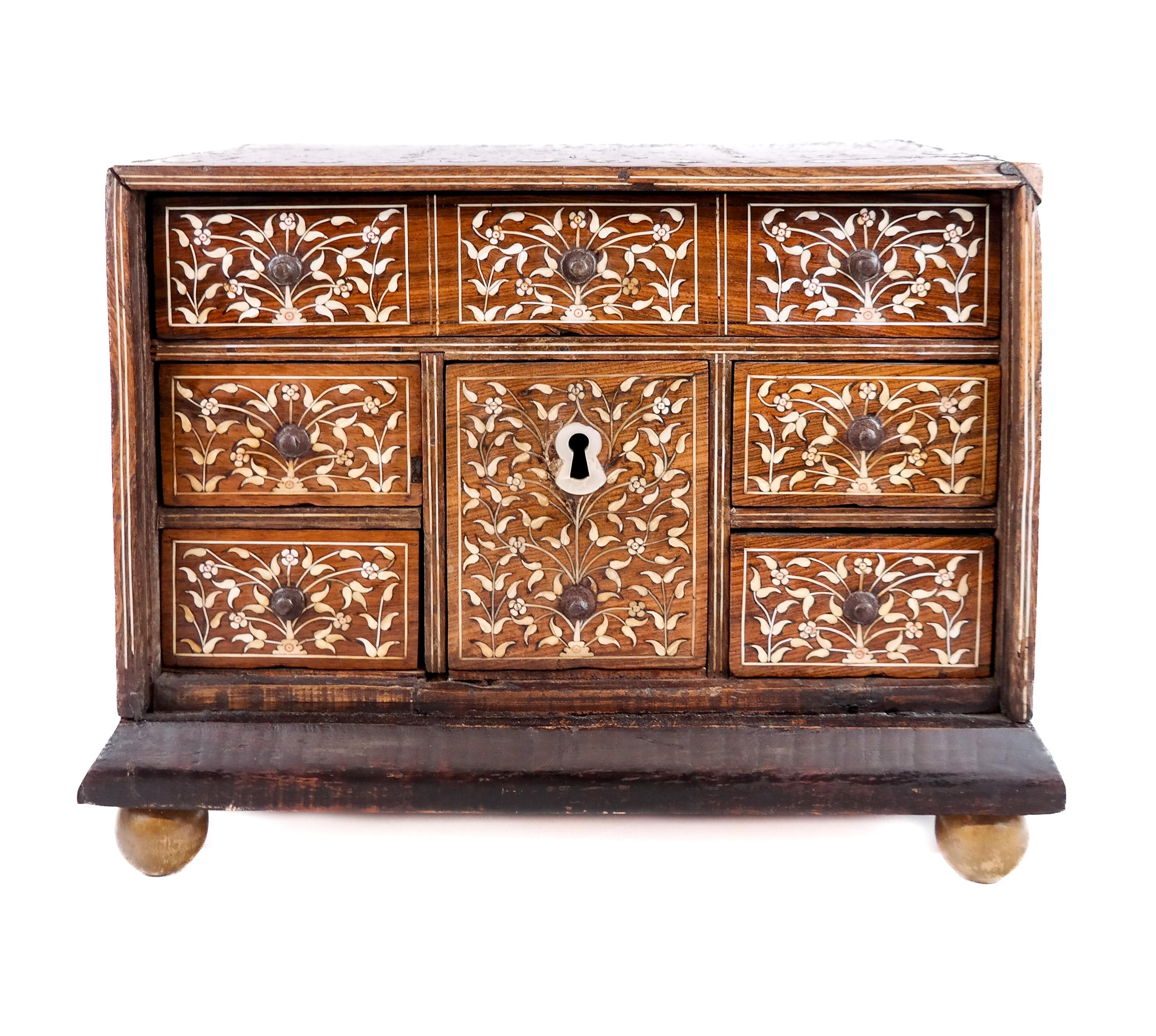 Mueble de mesa de marquetería con seis compartimentos y dos tiradores. Se trata de una caja artesanal bellamente decorada que refleja la artesanía y las influencias culturales de Goa durante el periodo colonial. Goa, antigua colonia portuguesa de la