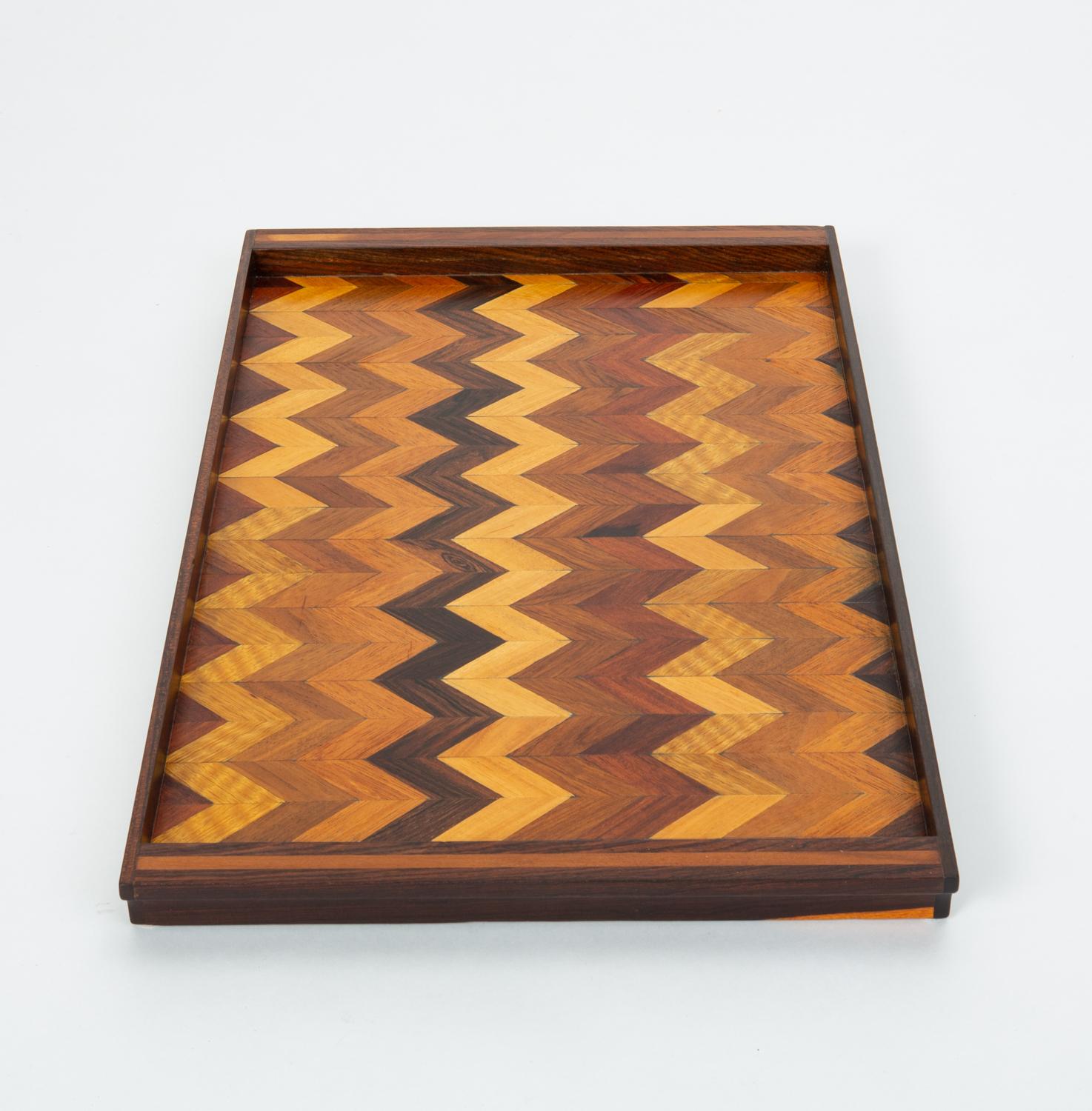 A rosewood serving tray by Don Shoemaker for his company Señal in the 1960s. The surface of the tray has a repeating chevron marquetry pattern in a gradient of local Mexican hardwoods. The narrow ends of the rectangle are slightly scooped to form a