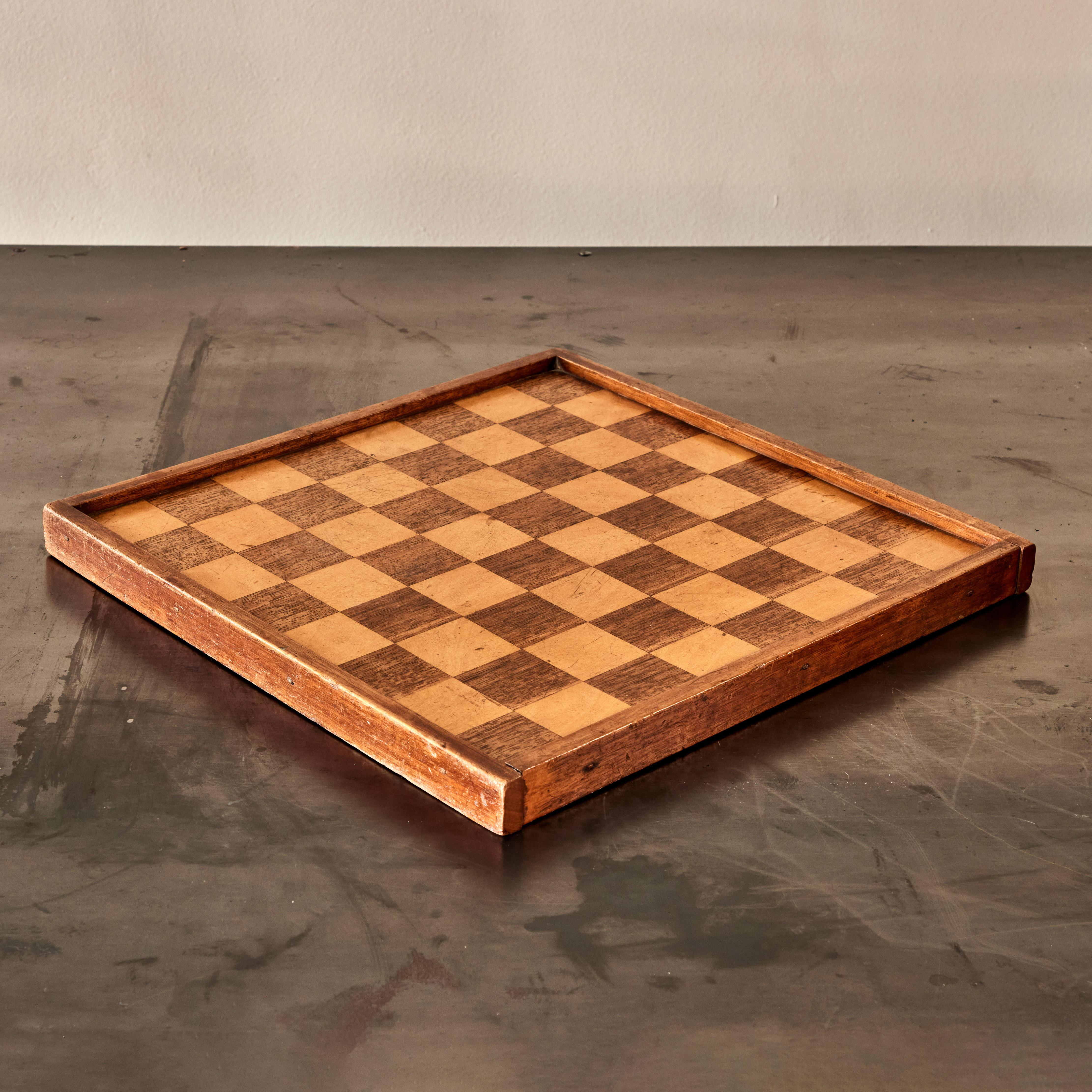 Inlaid wooden checkerboard from England, dating to the early 19th-century. An attractively patinated piece, it conceals an additional solo noble board on its underside. An excellent example of the elegance and functionality which define English