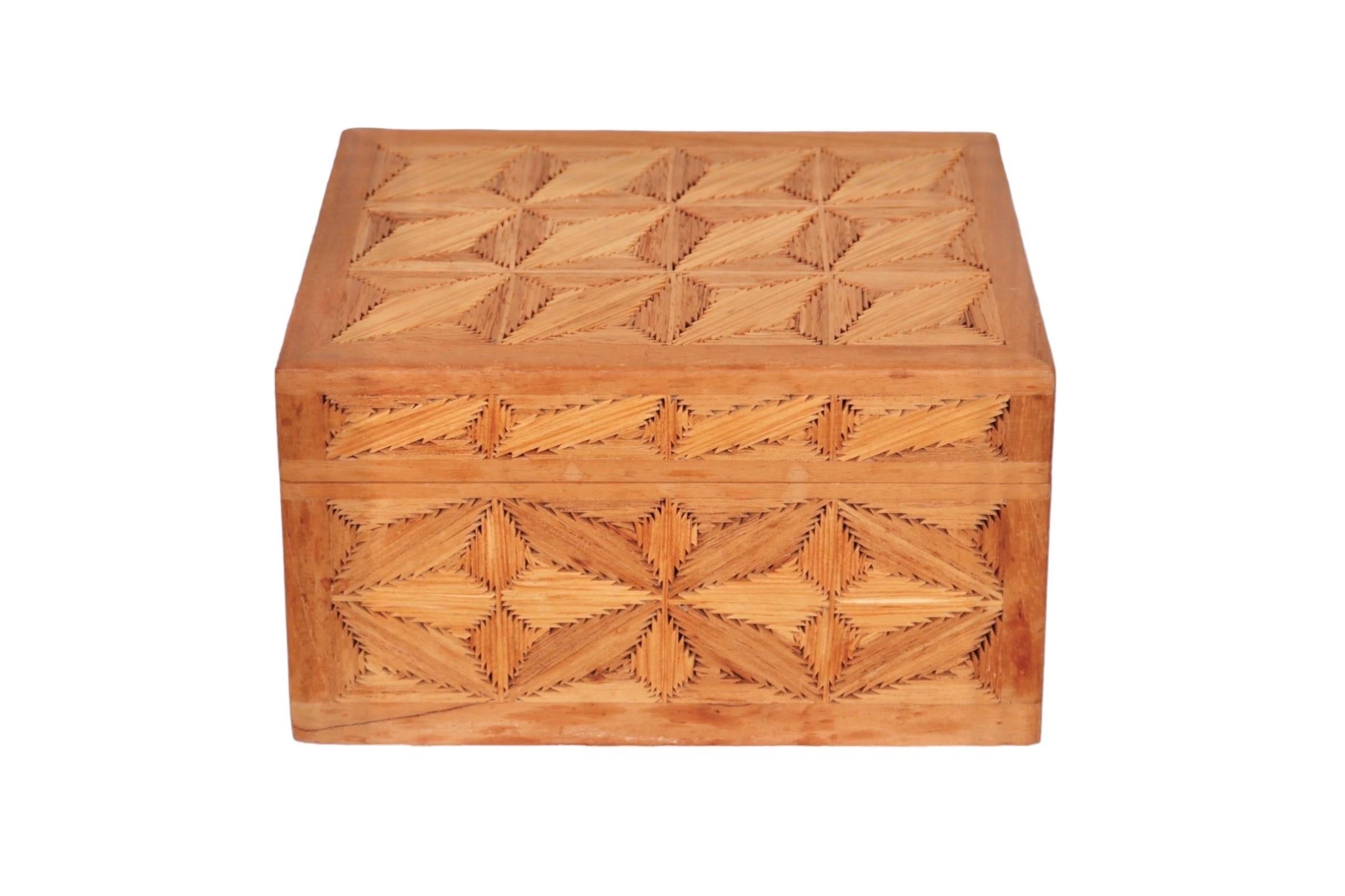 A handmade trinket box made of wood. Each side is inlaid with opposing wooden diamonds made of slivers of angled wood to create a simple geometric pattern. The lid opens with two hinges. 
