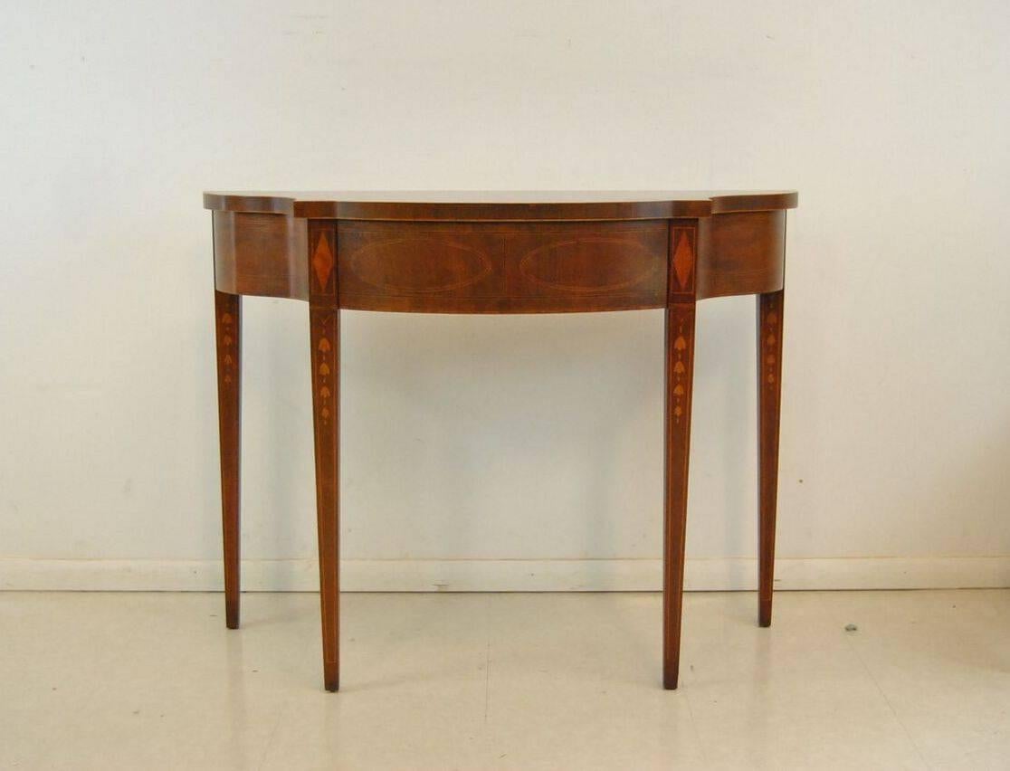 A very nice hall table/console table by Baker Furniture from the Historic Charleston Collection. This hall table features a very nice inlay pattern throughout. The tapered legs feature a drop down bell inlay pattern. The front features a nice oval