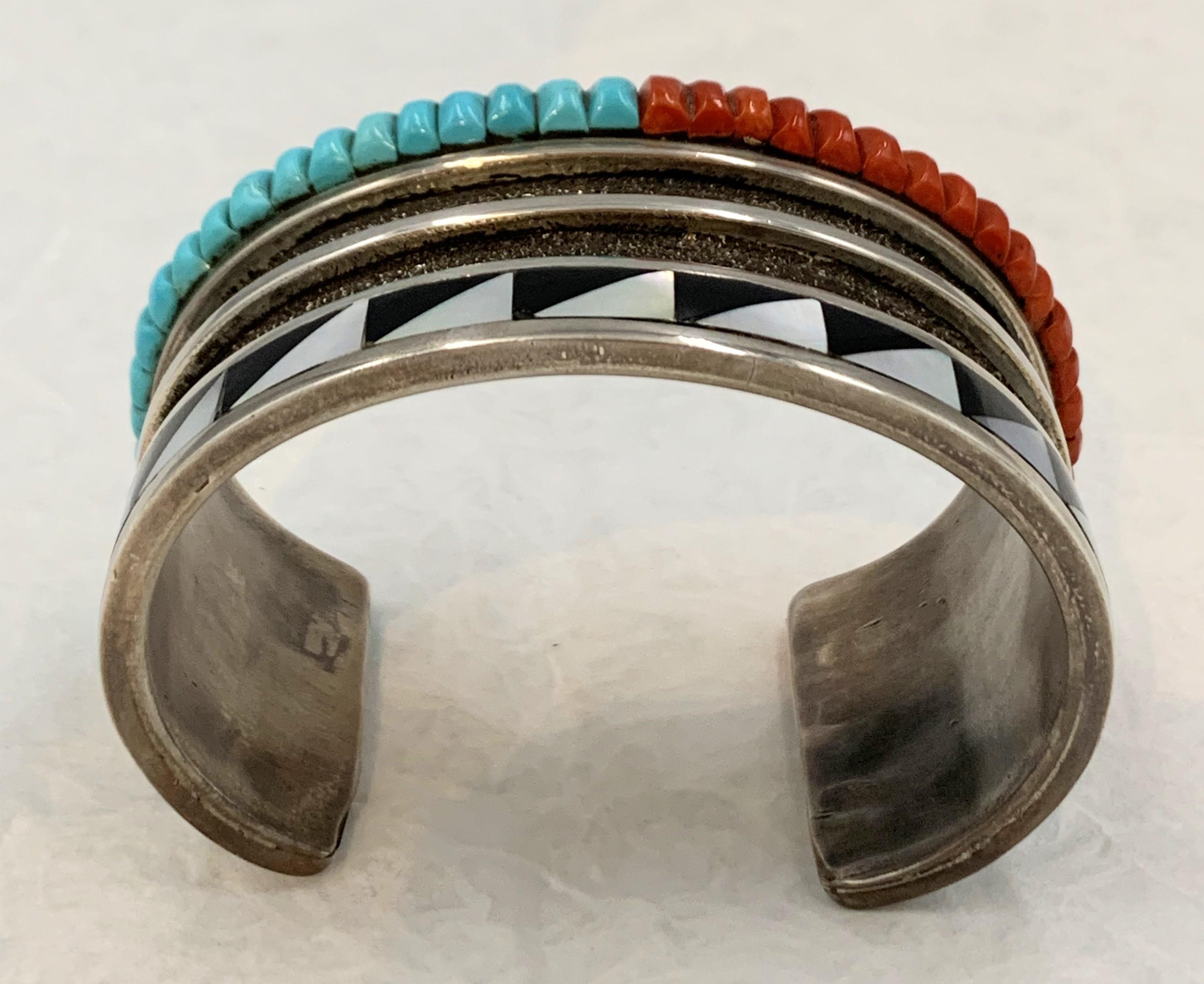 Heavy gauge sterling silver cuff with a row of coral and turquoise stones and jet and mother of pearl inlay. This exceptional cuff is handcrafted by Hopi silversmith Chimney Butte and his wife Nugeum. The 1 1/2” cuff is 5 1/2” inside with a 1 3/8”