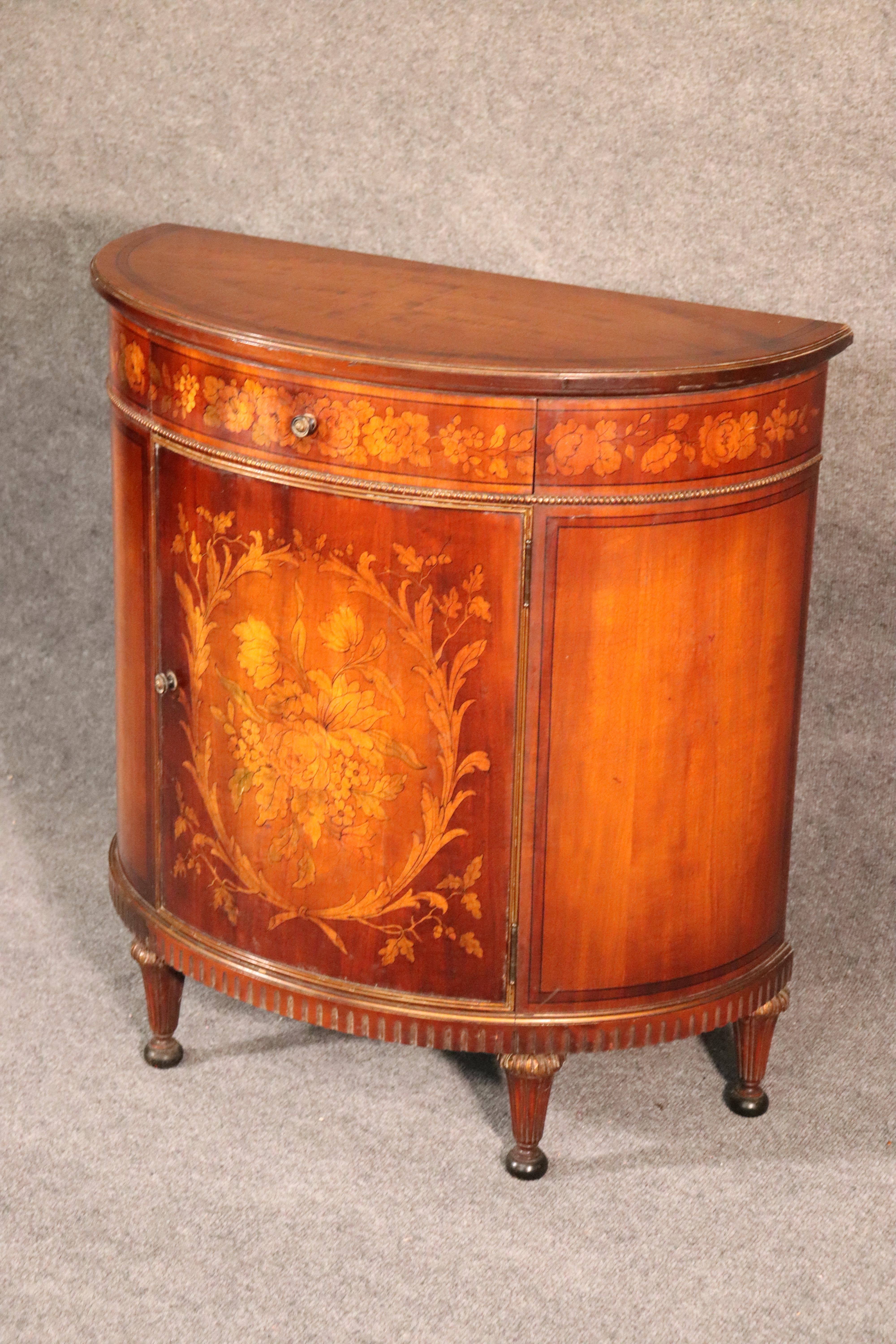This is a superbly inlaid demilune Adams style commode made in Michigan during the 1920s. The commode is in pristine vintage condition with only the most minor signs of use and no damage. The cabinet measures 30 wide x 32 tall x 14 deep.