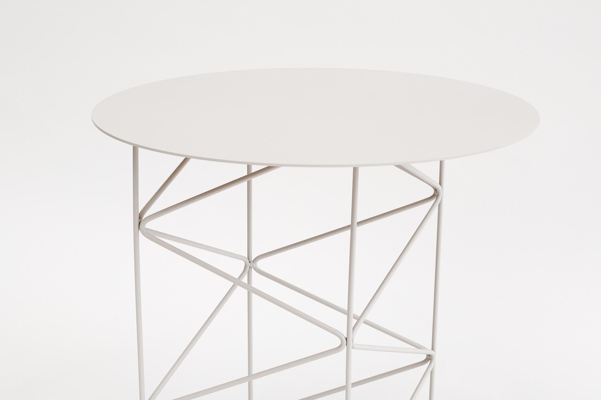 Inspired by the high-tech architectural movement, the INOS side table celebrates the aesthetic value of its metal structure. The stark lines of the welded steel frame create an ever-shifting geometry of light and shade as one moves around the