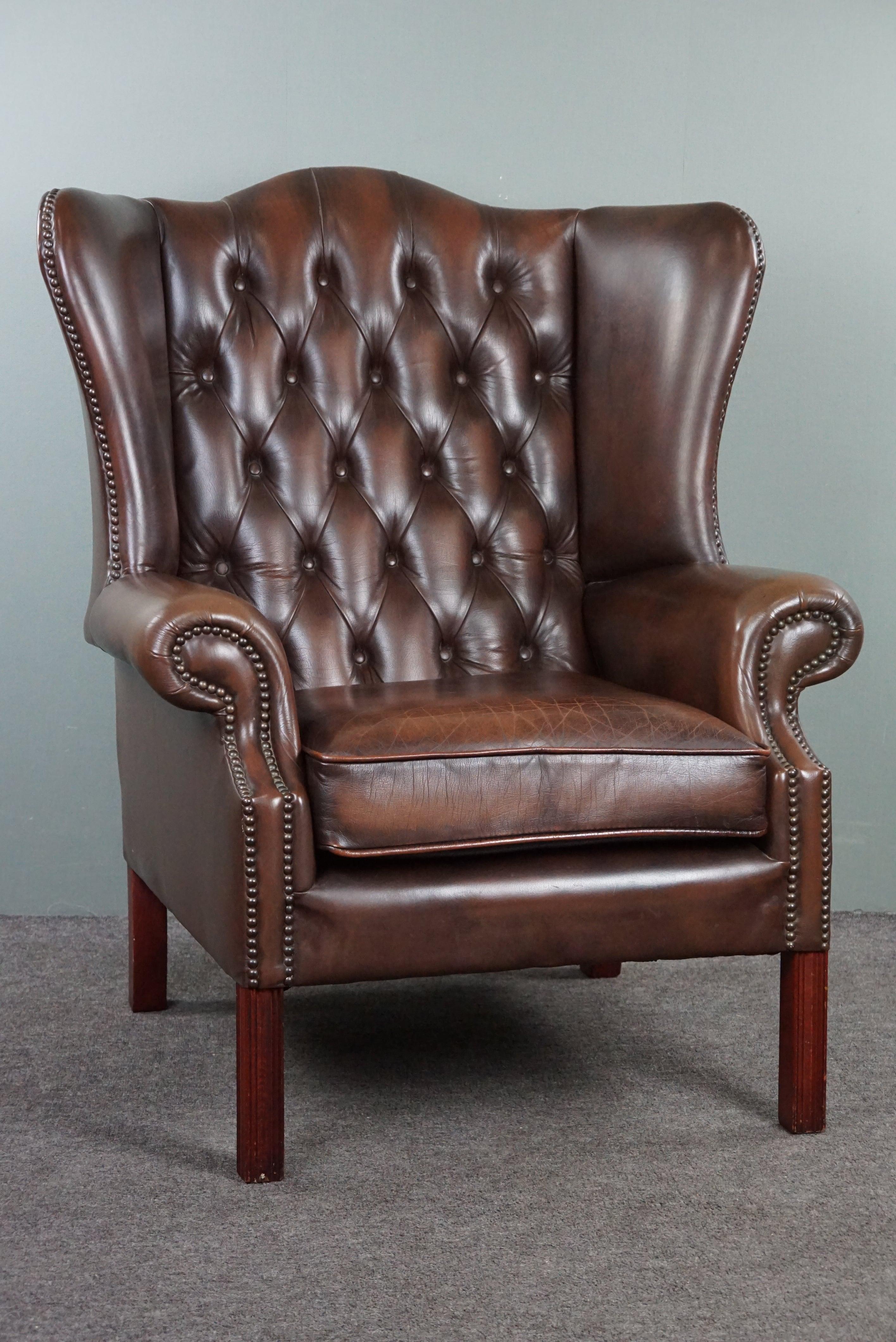 With pride we offer you this fantastic Chesterfield wingback armchair.
This armchair offers an exceptionally high-quality seating experience, and the combination of the leather, decorative nails, and wooden legs make it a true eye-catcher. The