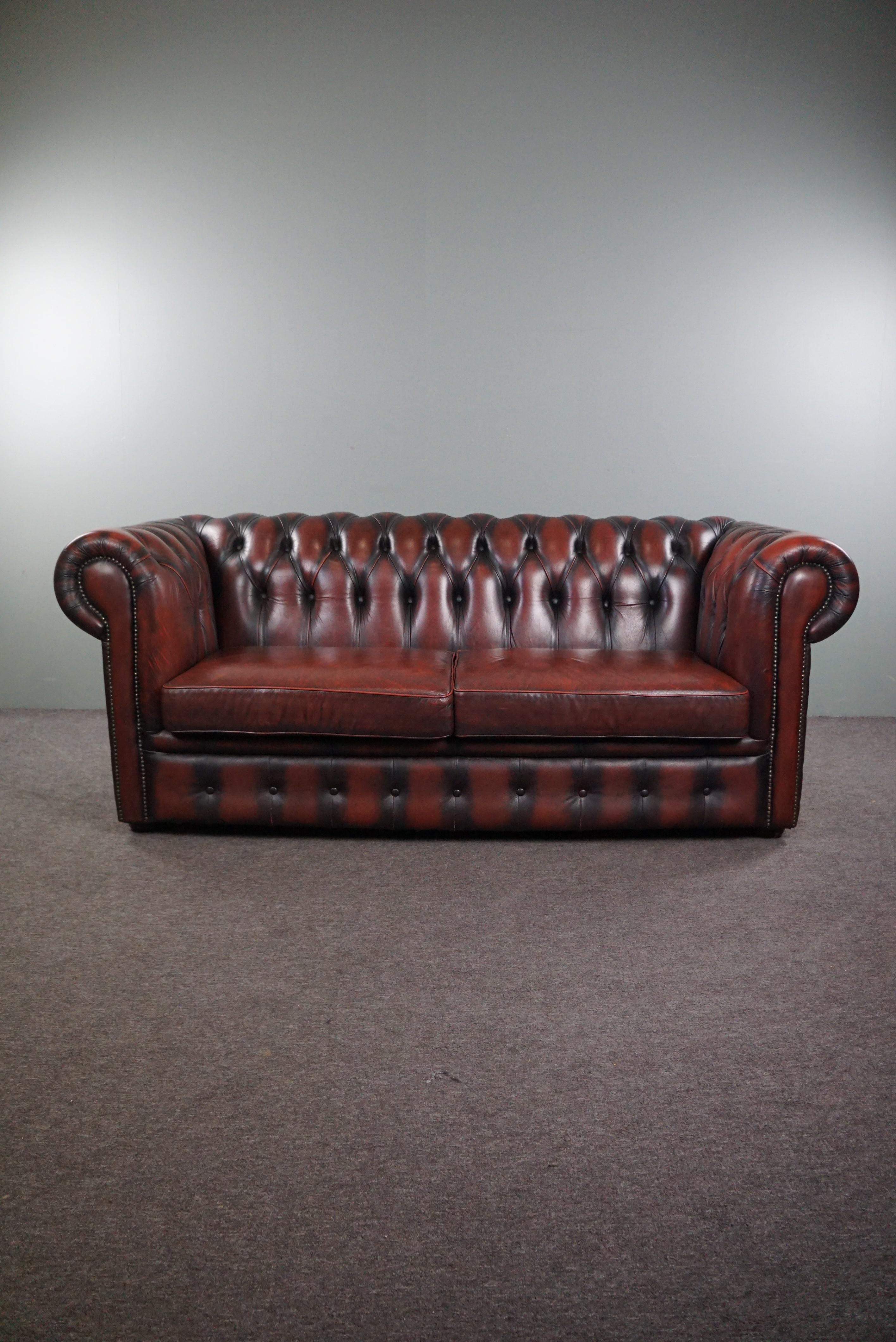 With pride we offer you this stunningly colored red cowhide Chesterfield sofa, spacious 2-seater.

Presented is this wonderfully comfortable, distinctly colored cowhide 2-seater Chesterfield sofa. This deep red Chesterfield sofa features a tufted