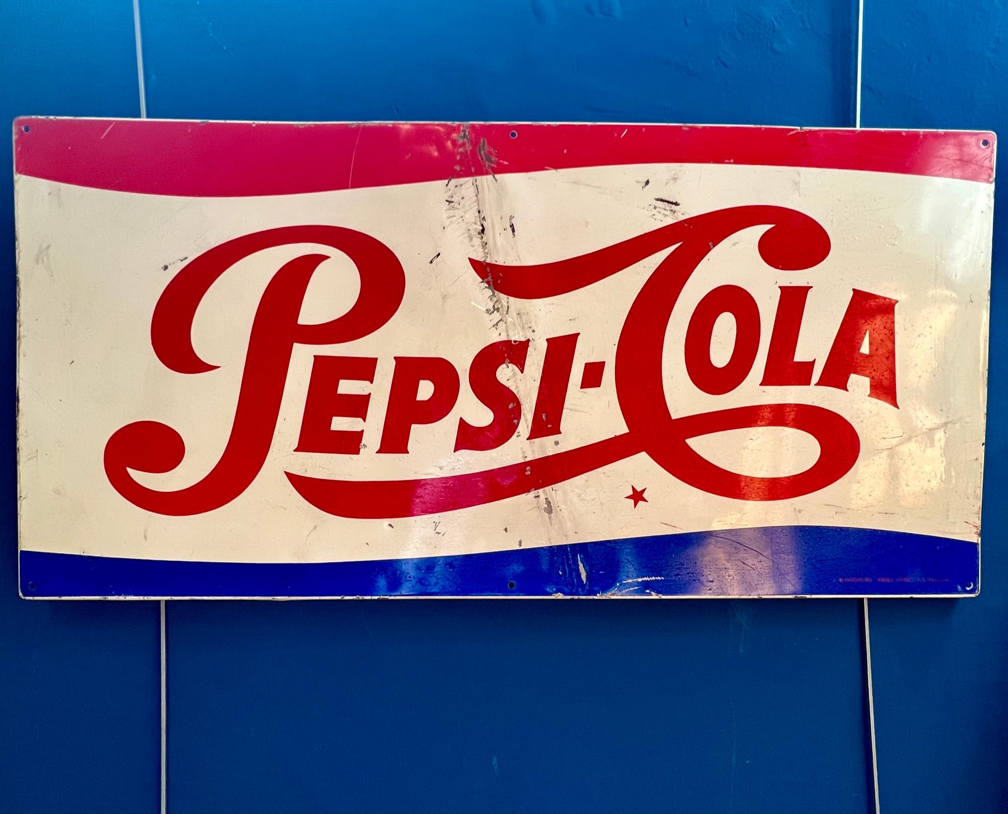 Iconic Pepsi-Cola advertising sign made of enameled metal, dating from the 1970s. 
The design incorporates the classic logo with red cursive lettering, set against a wavy background in shades of white, red and blue, evoking the palette of the