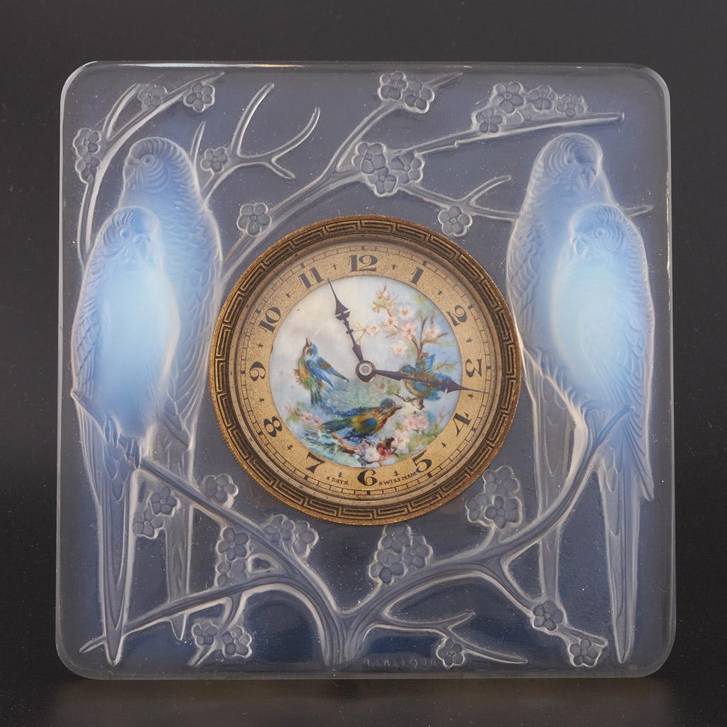 Inséparables, une horloge en verre Art déco de René Lalique (1860-1945). Moulée en relief avec deux couples d'amoureux bleu opalescent assis sur des fleurs de prunus. Cadran d'horloge en émail peint à la main représentant une scène de fleurs et