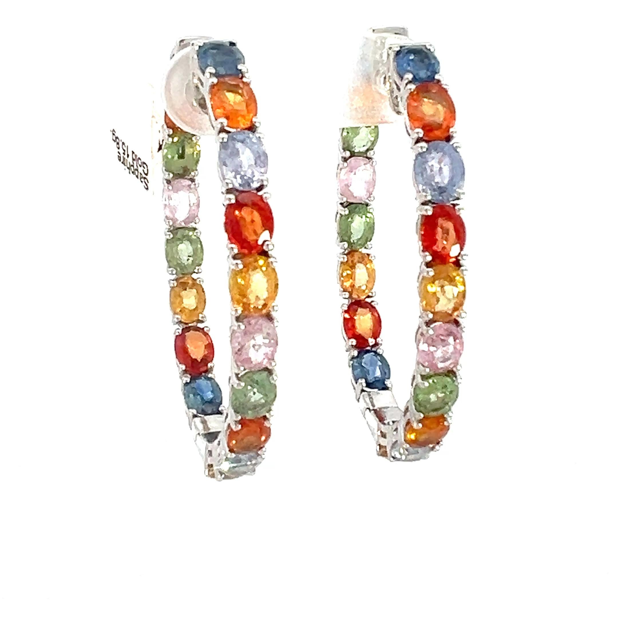 18K white gold inside-out hoop earrings featuring a vibrant array of bold, multi-color sapphires. Expertly crafted, each earring is adorned with 18 oval-cut sapphires, meticulously set to create a dazzling spectrum of color that radiates brilliance