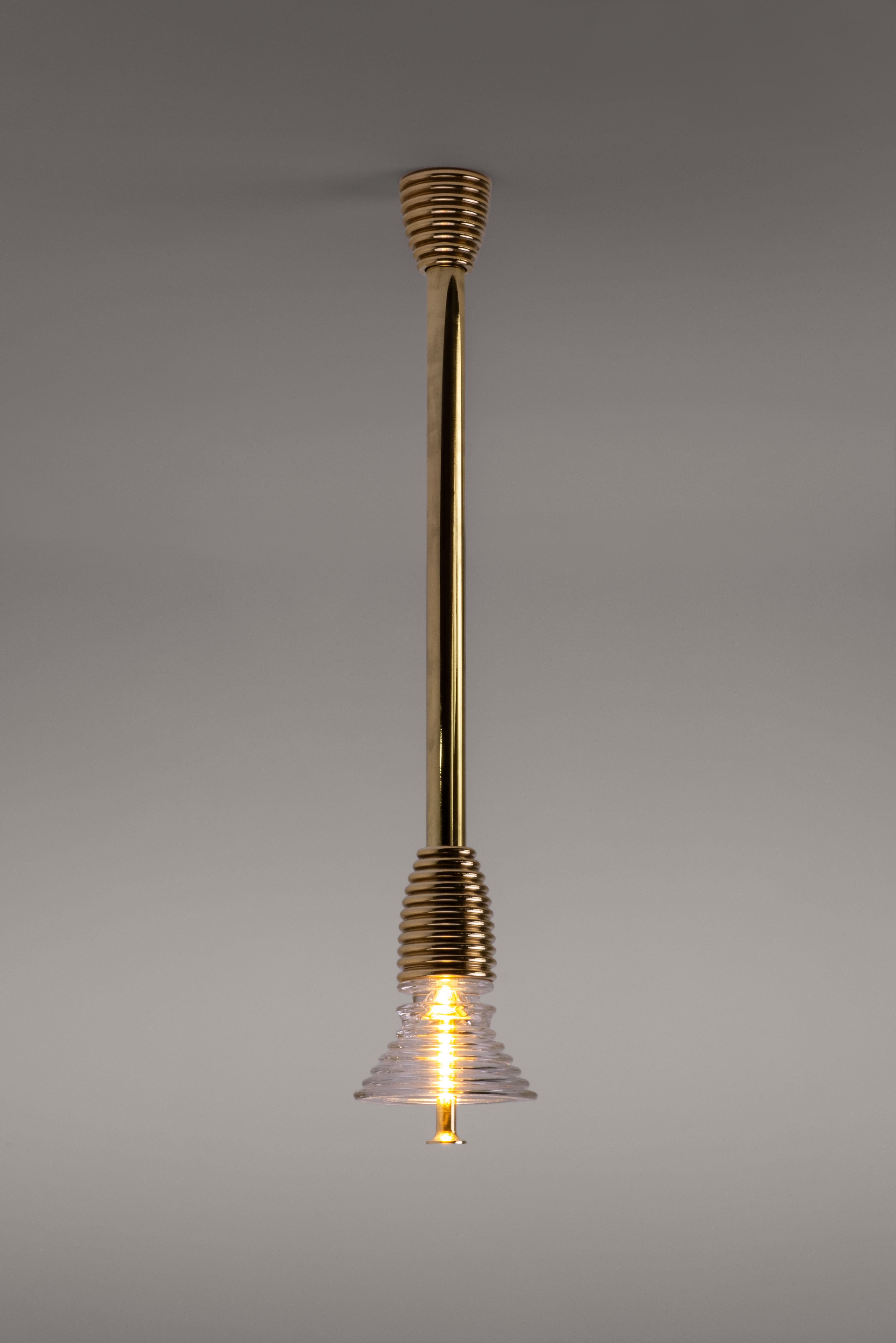 Insulator A Clear Glass and Polished Brass Pendant Light by Novocastrian
Dimensions: Ø 14 x H 21 cm. Rod lenght: 85 or 125 cm.
Materials: Clear glass and polished brass.  

All products are available in custom dimensions and finishes. Rods can be
