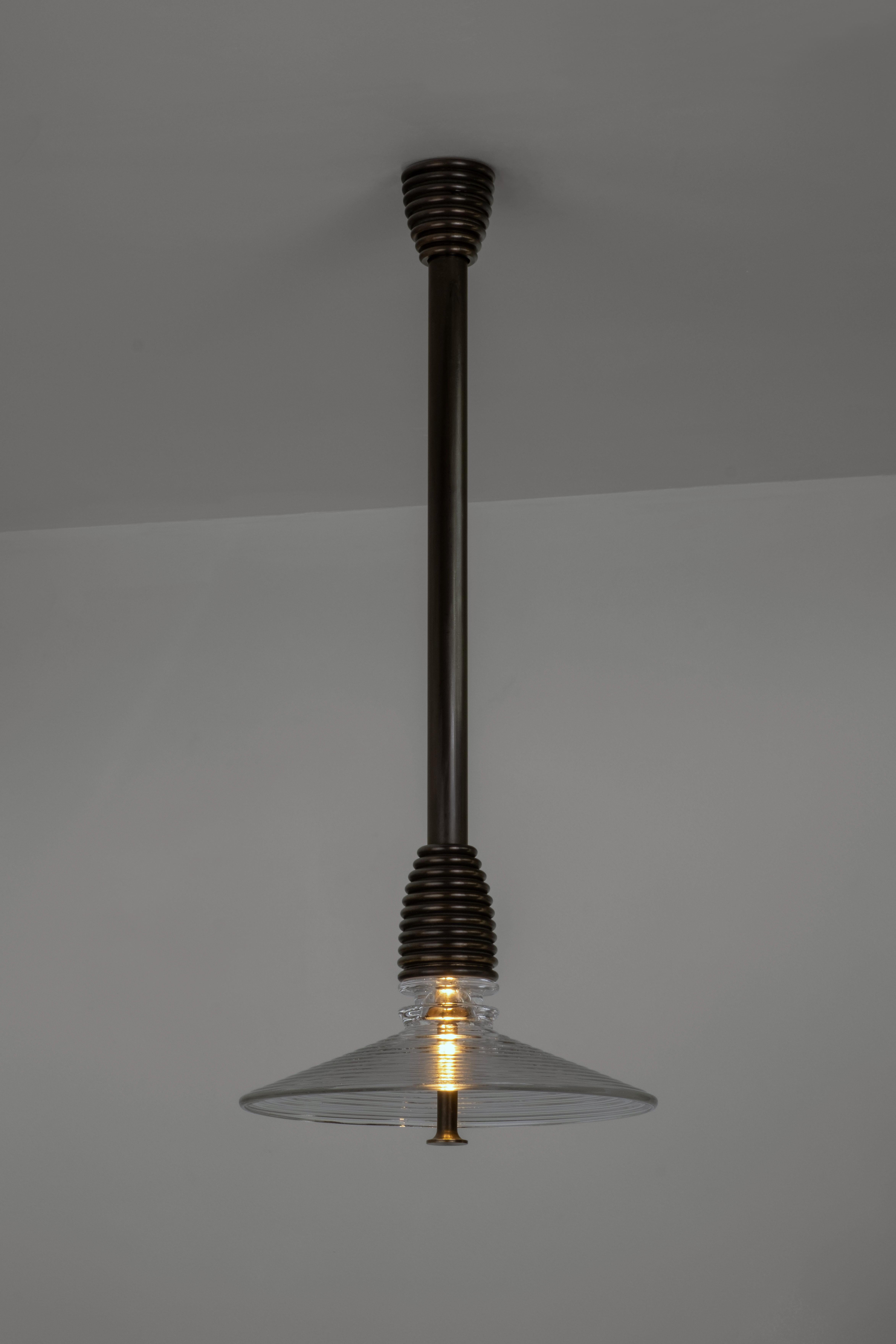 Insulator B Clear Glass and Dark Brass Pendant by Novocastrian
Dimensions: Ø 32 x H 21 cm. Rod lenght: 85 or 125 cm.
Materials: Clear glass and dark brass.  

All products are available in custom dimensions and finishes. Rods can be cut to length or