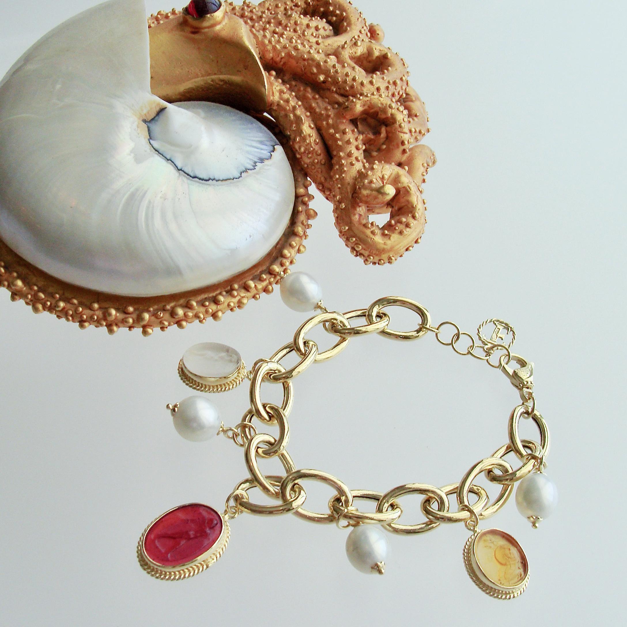 A unique gold vermeil link bracelet  has been artfully adorned with three Venetian glass intaglio charms which alternate with smooth and creamy freshwater pearls.  Each of the intaglio charms has been carefully set into a millegrain bezel which