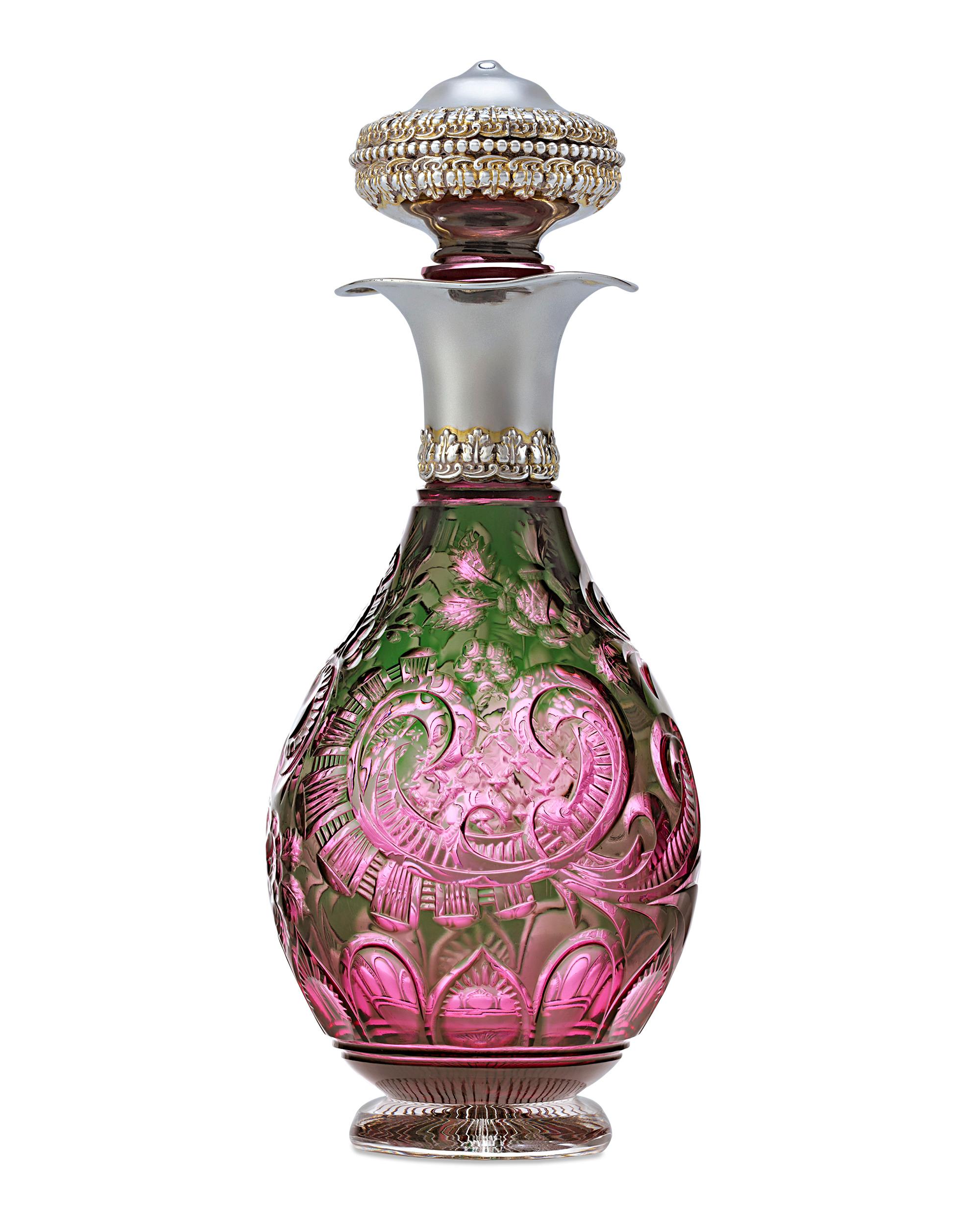 This charming intaglio cut glass perfume bottle boasts gorgeous color and an enchanting design. Masterfully crafted by celebrated English glassmakers Stevens & Williams, the scroll and foliate design is brilliantly cut from vibrant green to