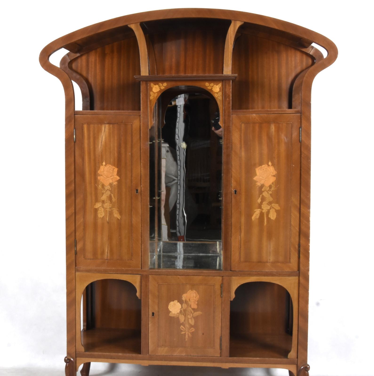 Fantastic display and storage cabinet constructed around the turn of the century in France. Beautiful Art Nouveau lines crown this showcase. Constructed in Mahogany, intarsia floral inlays adorn the facepieces. All hardware and glass are original