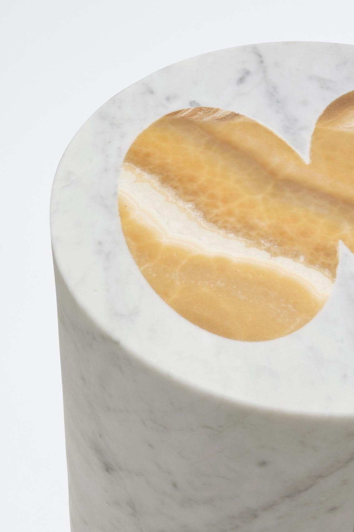 Tabouret cylindrique en Carrare blanc avec des marqueteries en Onyx miel comme substitut de la personne qui s'y assoit. Elle peut également être utilisée comme table d'appoint. Cette pièce fait partie de la collaboration entre Sunnei et Bloc