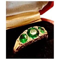 Intense and brilliant three stone tsavorite stones in gold setting.