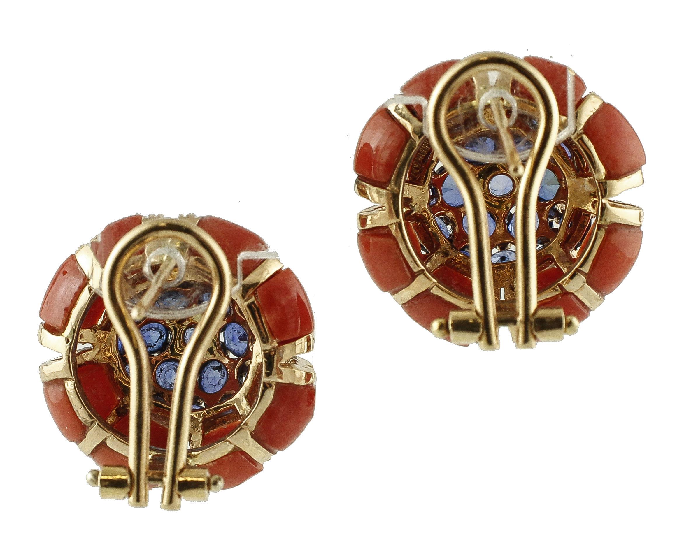 Faboulus pair of earrings realized in 14k rose gold structure. These earrings feature a central core studded with blue sapphires a round frame of beautiful red rubrum coral. The earrings are embellished with details in rose gold and diamonds. 
These