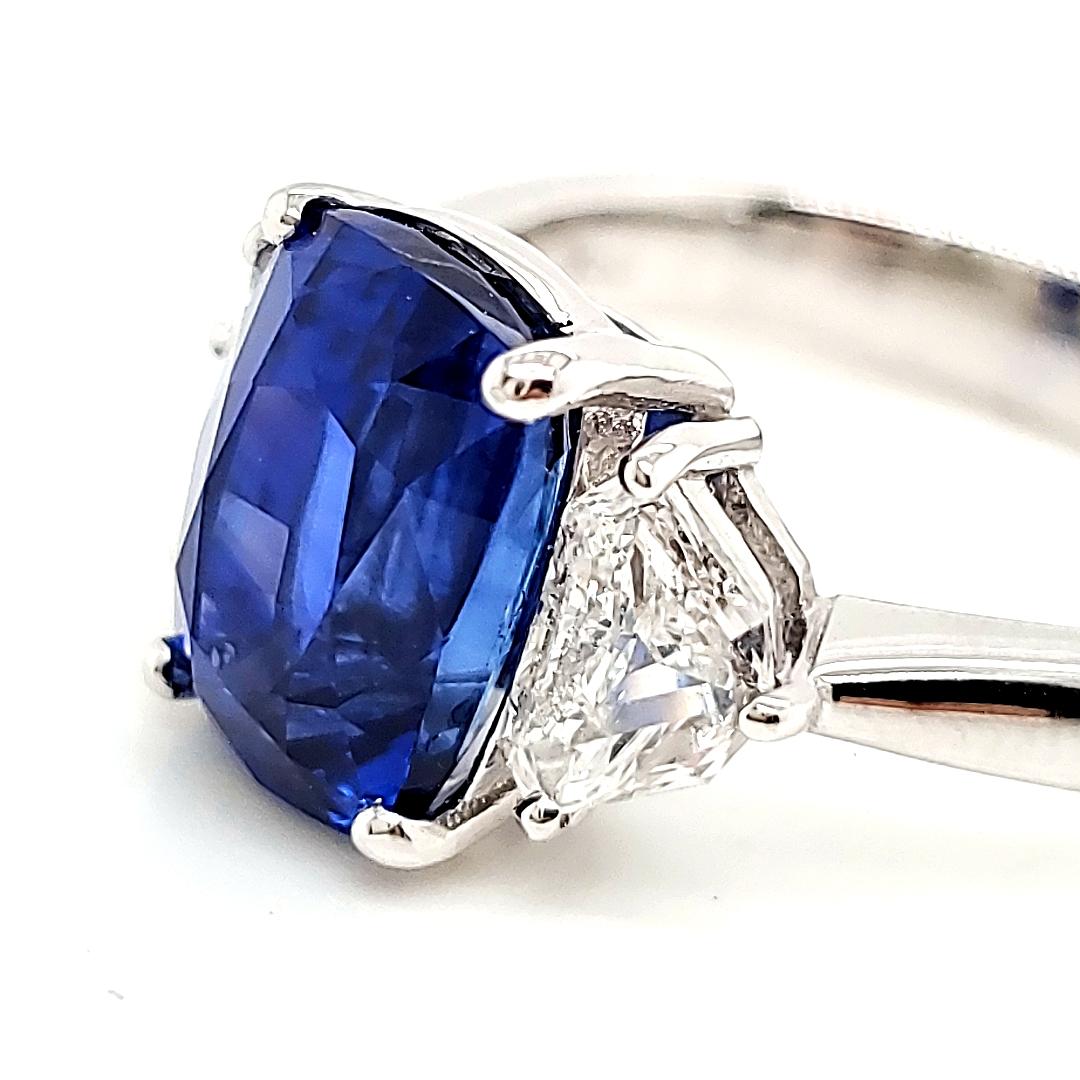 At the heart of this exquisite ring lies a captivating heated sapphire cushion weighing 4.47 carats, boasting a mesmerizingly intense cornflower blue hue—a true testament to its rarity and quality. 

It is sourced from Sri Lanka and comes with a GRS