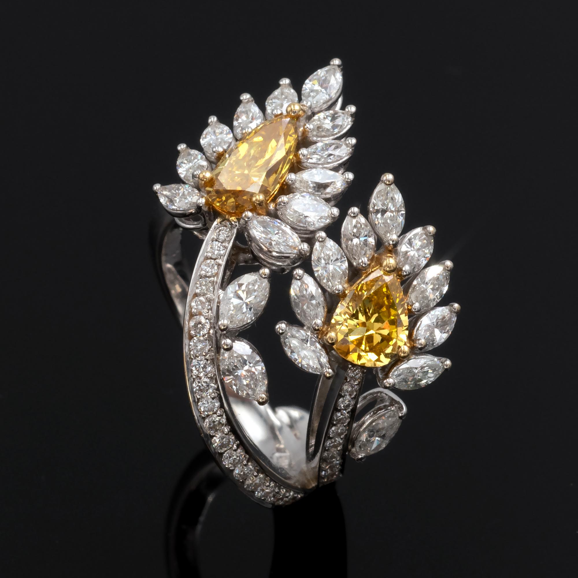 Exquisite ring with a delicate design and outstanding make consisting of two 18KT white gold spikes set with diamonds wraping around the finger.  

The two center stones are pear shapes very intense yellow fancy diamonds weighing 1,22 carat.