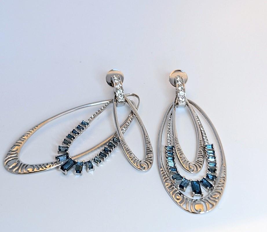 The Interchangeable Earring Ensembles are the foundation of the Lyra Collection. Lightweight and playful, this ensemble consists of the huggie earring with blue and white topaz and three hoop elements. The huggies and the small and large hoops are