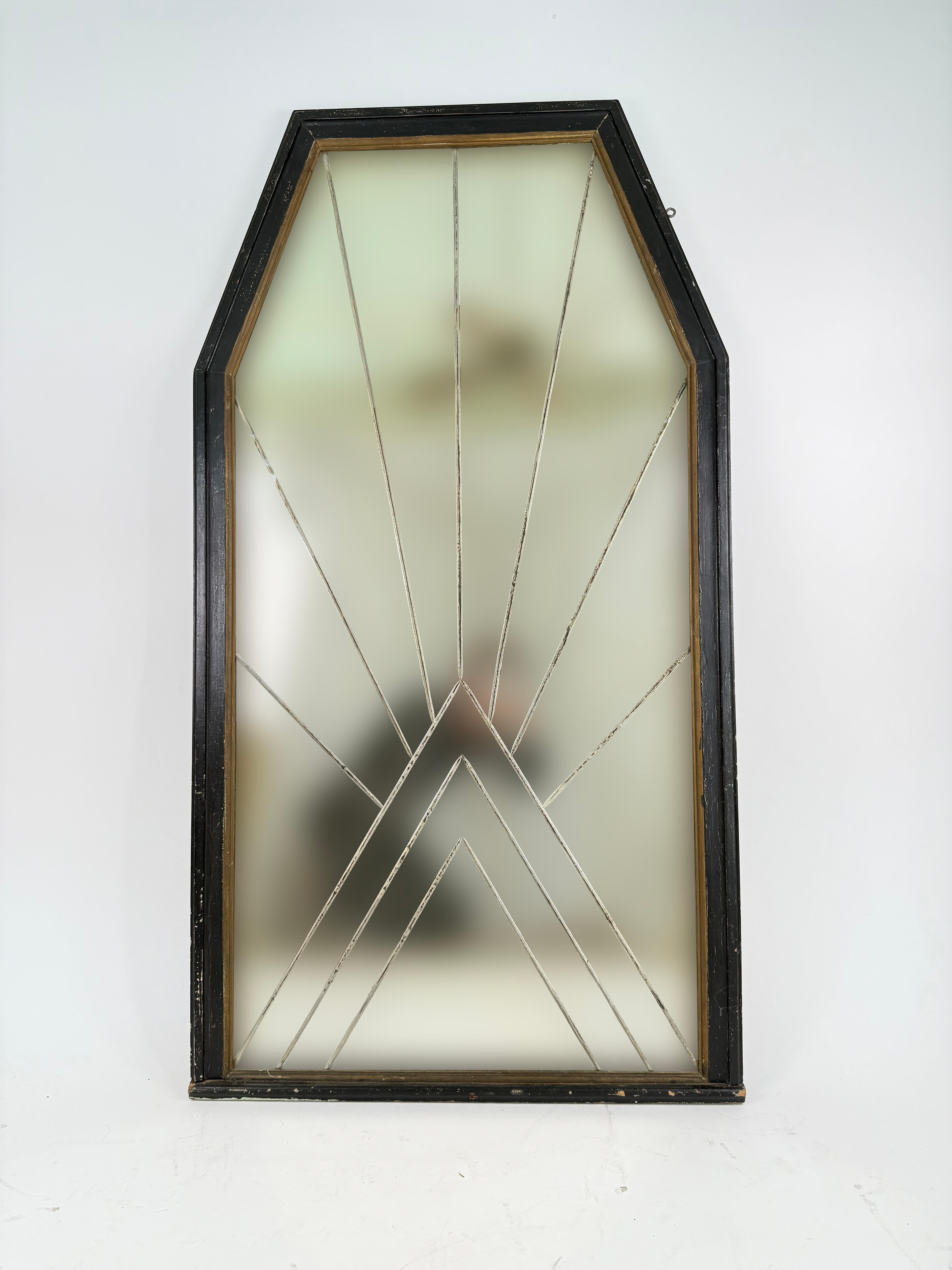 This distinctive Art Deco Mirror is etched on the underneath side with bevelled lines creating a bold geometric starburst-like pattern.  The mirror itself displays a beautiful patina with dark spots, loss and some hazing.  The frame has a worn