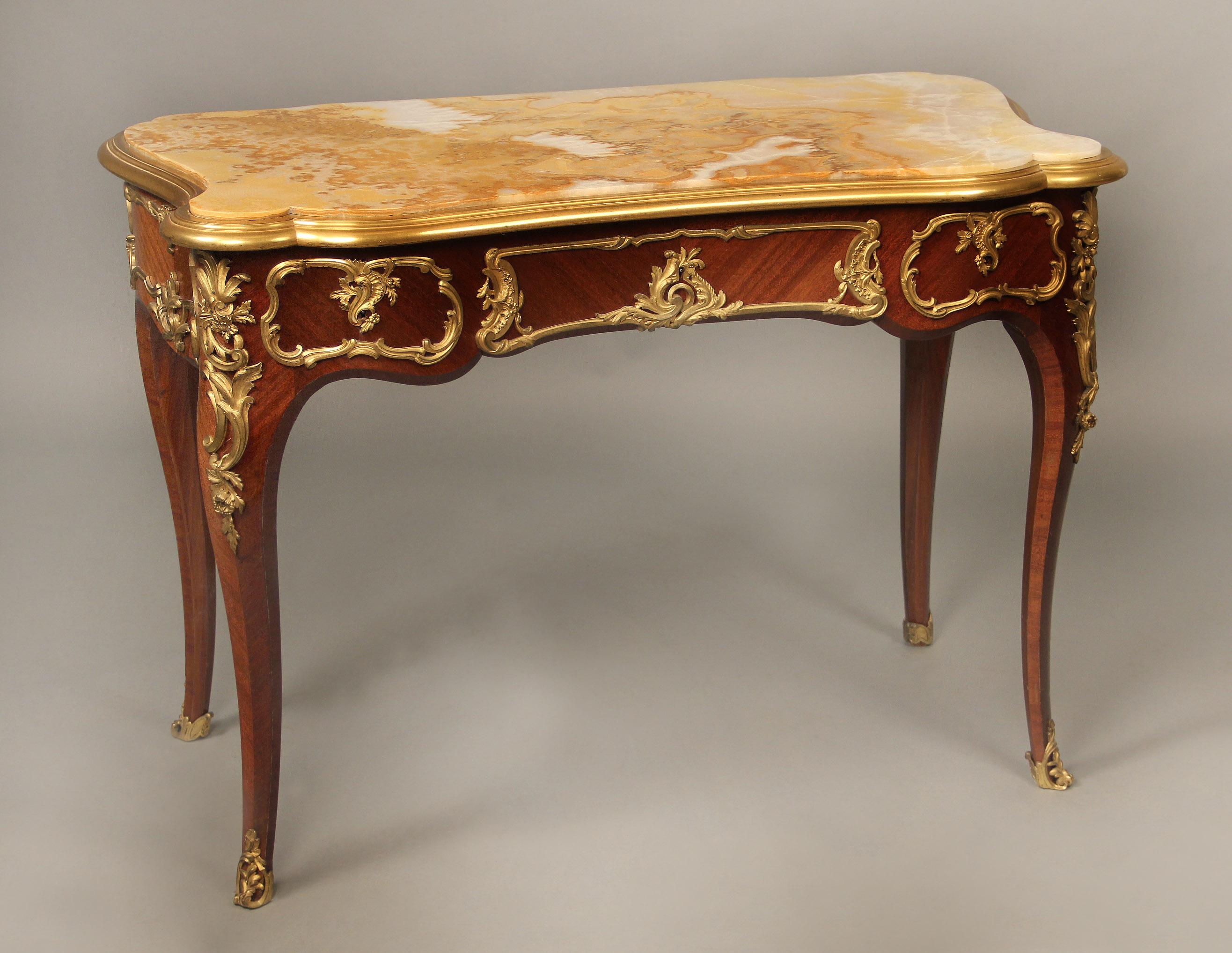 An Interesting Late 19th century Gilt Bronze Mounted Louis XV style onyx top side table By Henry Dasson

Henry Dasson

The beautiful shaped onyx top within a bronze rim, above a long centered and two small side drawers, the backside similarly