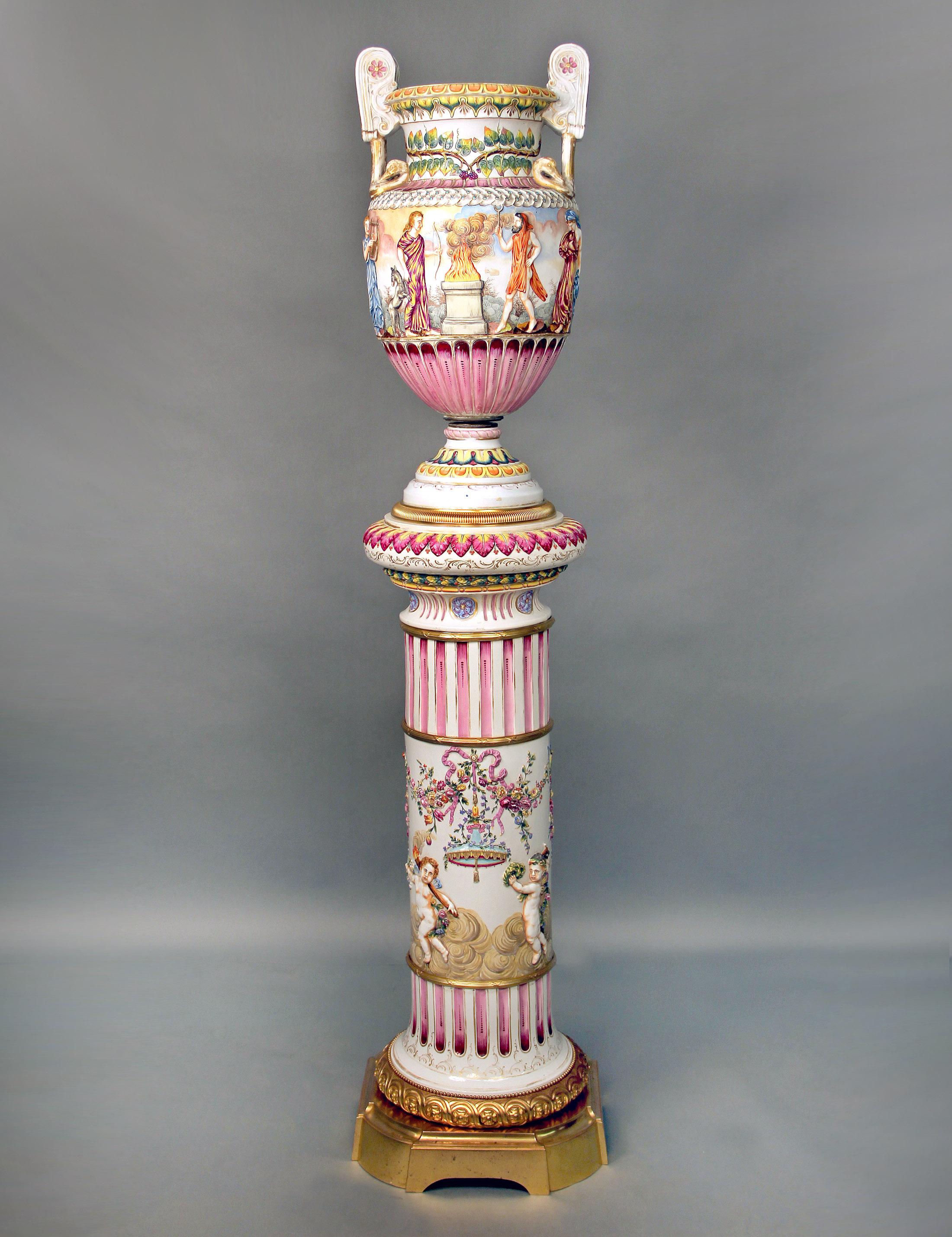 A large and interesting late 19th century gilt bronze and Italian Capodimonte porcelain vase and pedestal.

The vase with many different figures playing and holding instruments and weapons, centred around a flame, the top painted with vines,