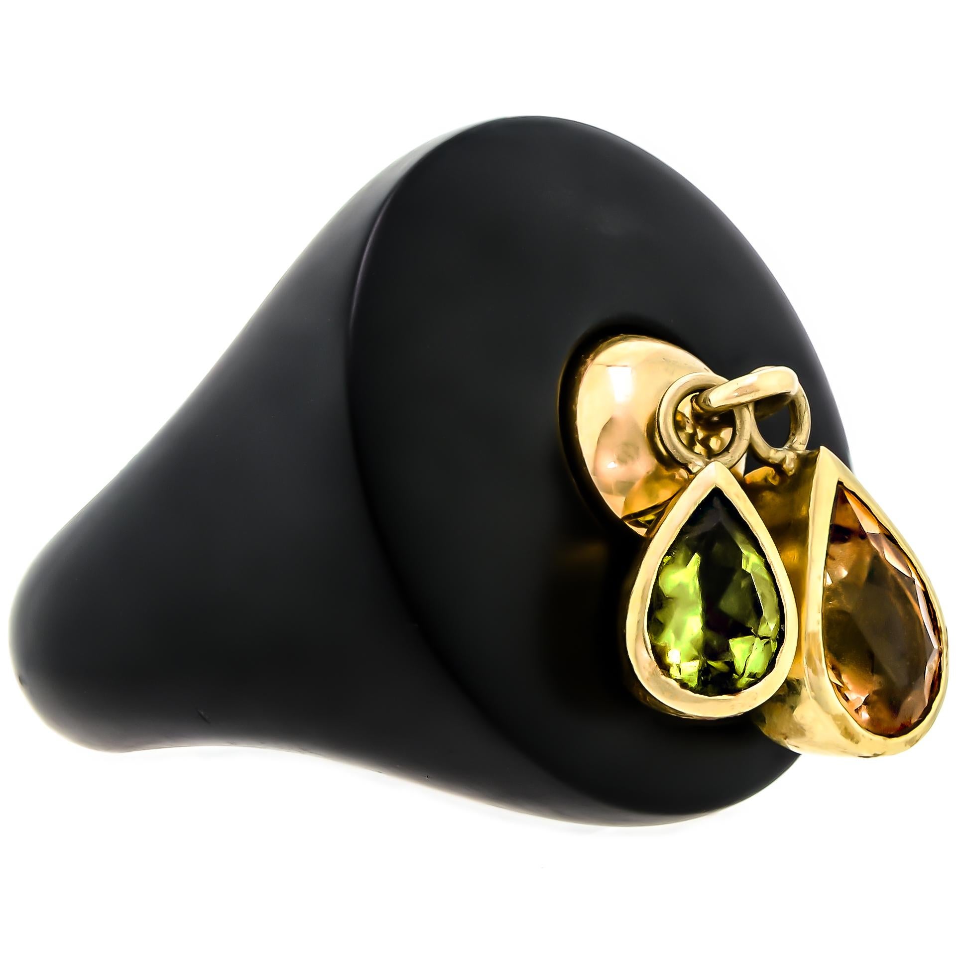 This exquisite cocktail ring is an absolute marvel of craftsmanship. The black resin dome at the center of the ring is a breathtaking sight to behold. The circular dome is adorned with two dazzling pear-shaped gems, one peridot, and one citrine,