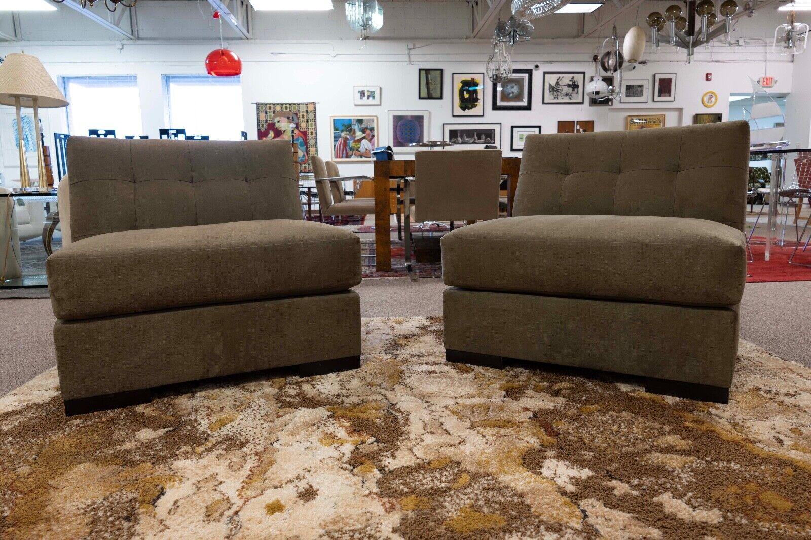 This pair of contemporary modern chairs by Interior Craft boasts a luxurious suede upholstery in a sophisticated taupe shade. The clean lines and simple yet elegant boxy design offer a modern aesthetic that pairs well with any contemporary decor.