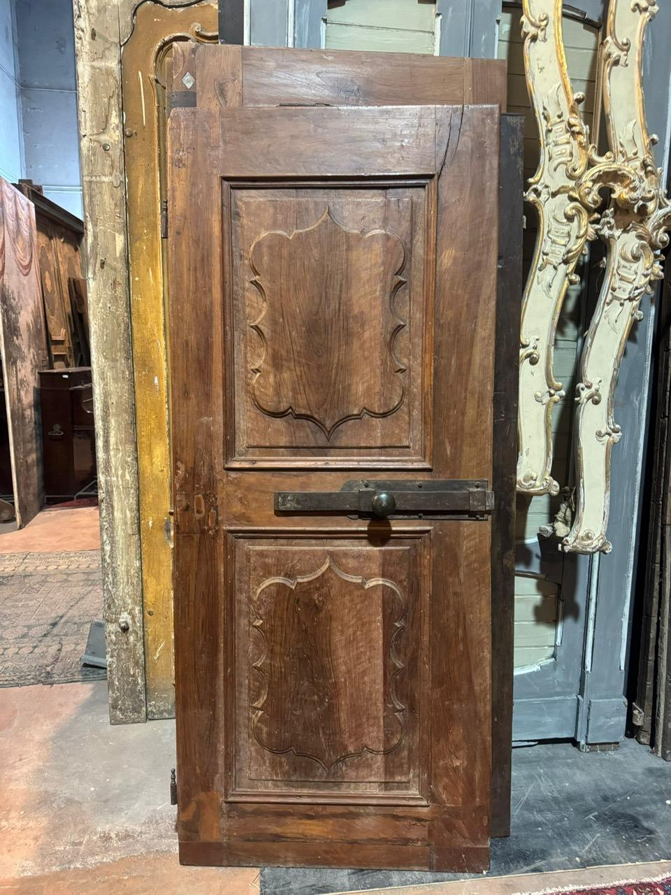Porte d'intérieur ancienne en noyer massif, une porte avec des panneaux sculptés ondulés, dos brut, elle conserve le loquet avant d'origine mais est sans cadre car elle a été montée directement sur le mur, d'origine italienne, original du 18ème