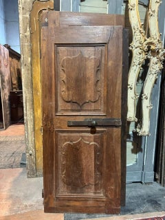 Interior door in walnut wood, one leaf with carved wavy panels, Italy