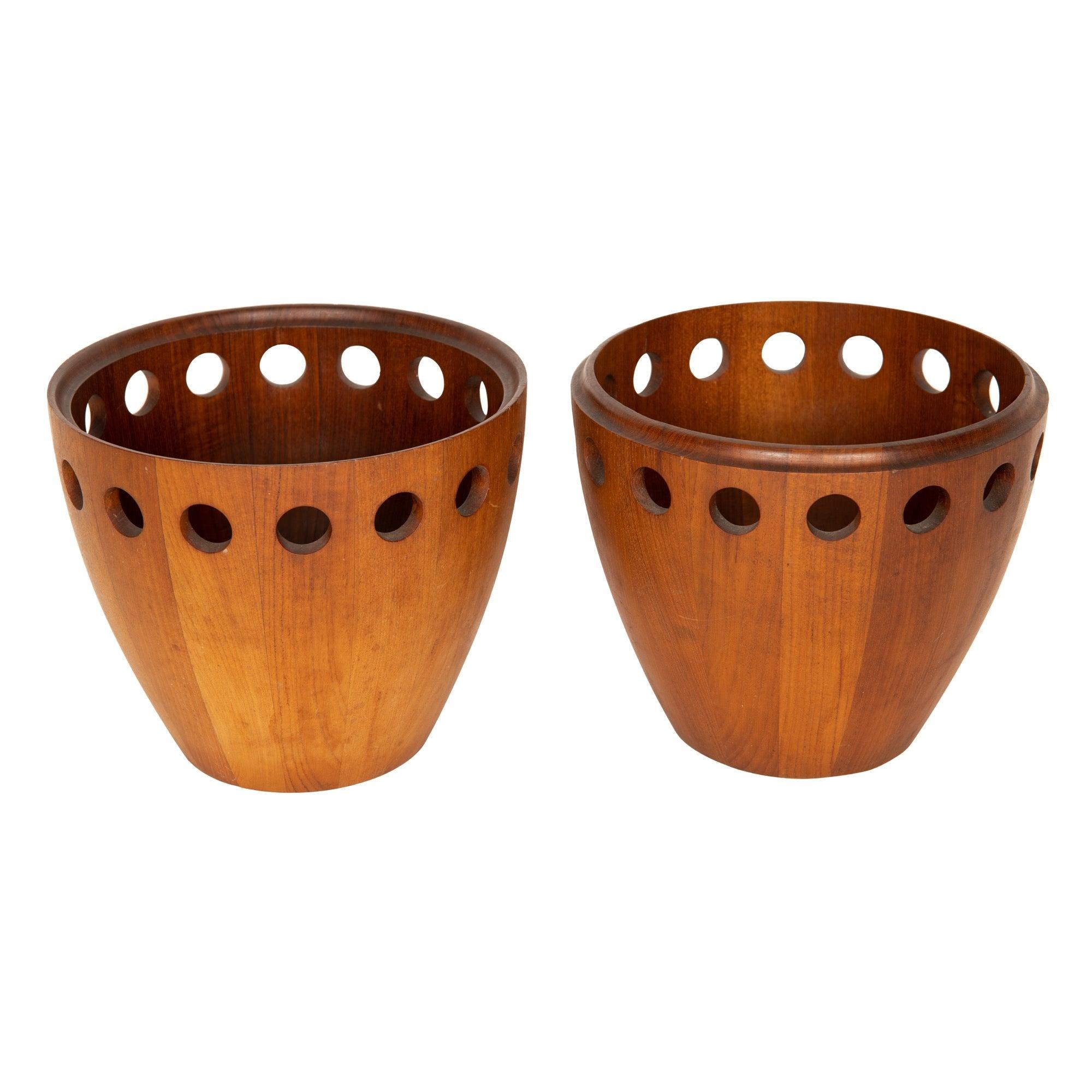 A pair of interlocking salad bowls in teak with perforated edges.