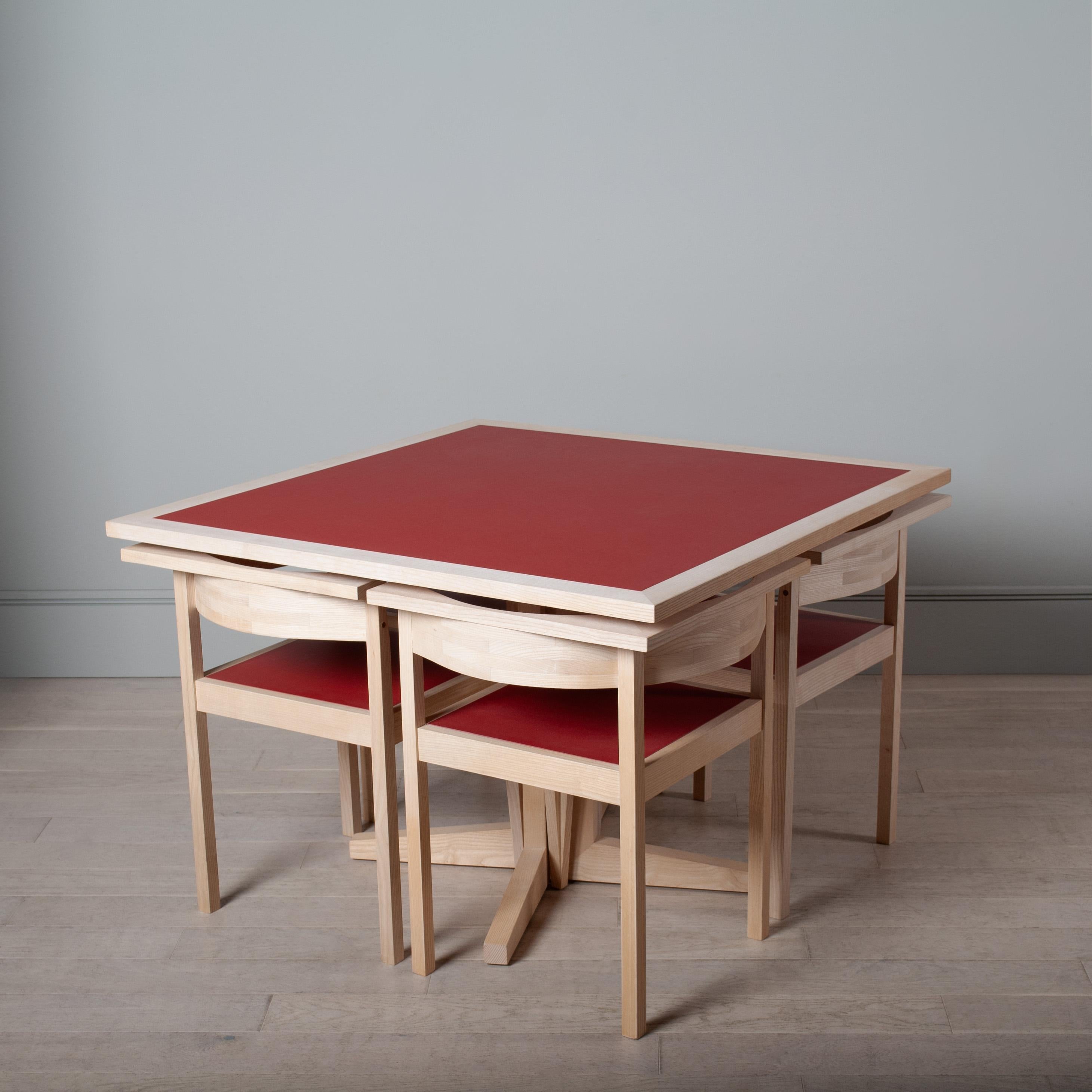 A one of a kind space efficient interlocking table and chair nest set.
Constructed from crisp white European Ash with inset red marmoleum. A lovely sharp angular design allowing the chairs to sit perfectly underneath the table. 
The chairs have a