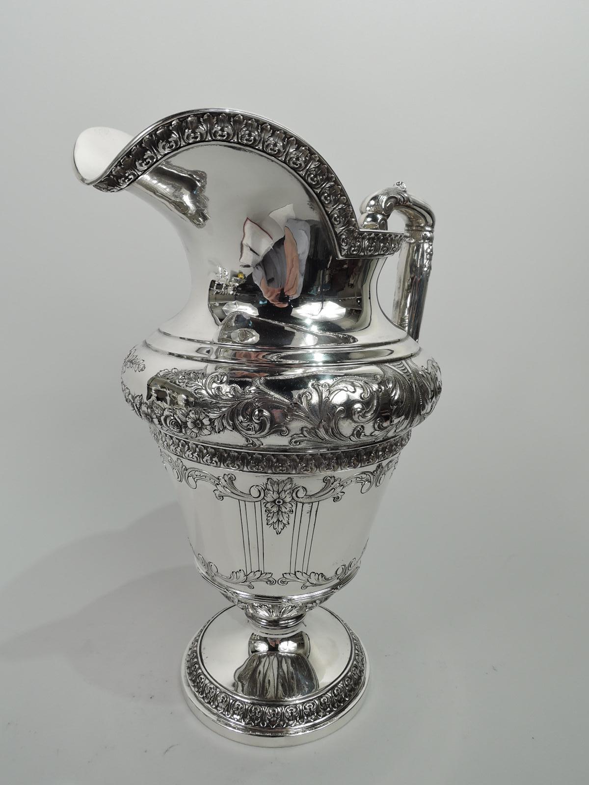 Marie Antoinette sterling silver water pitcher. Made by Meriden Britannia (part of International) in Connecticut, ca 1910. Round and tapering bowl in domed foot; bellied shoulder, helmet mouth, and leaf-capped scroll-bracket handle. Garland,
