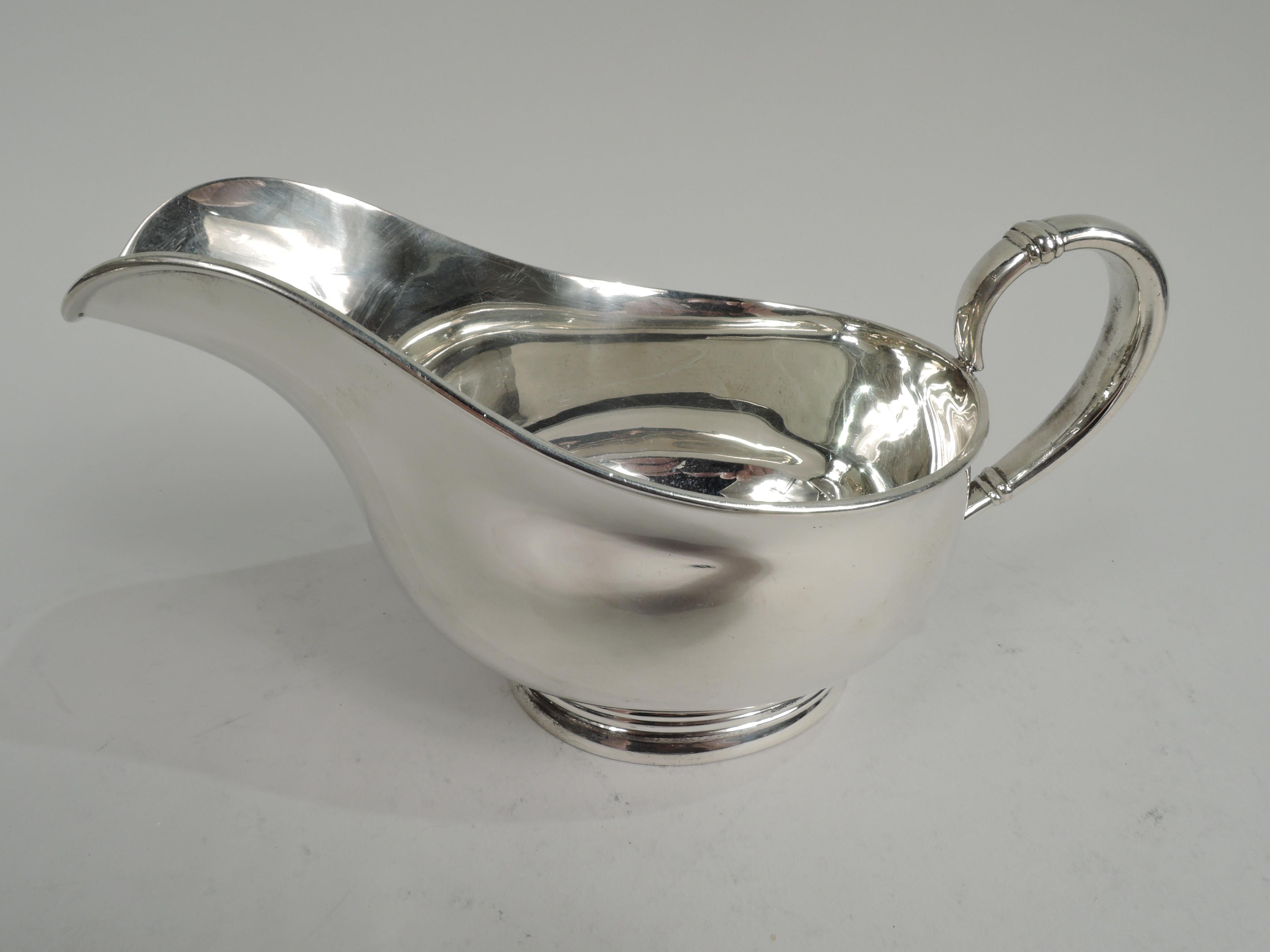 Royal Danish sterling silver gravy boat on stand. Made by International in Meriden, Conn. Boat bellied with helmet mouth, banded scroll handle, and oval reeded foot. Stand ovalish with pierced acorn motif at ends. Desirable pieces in the classic