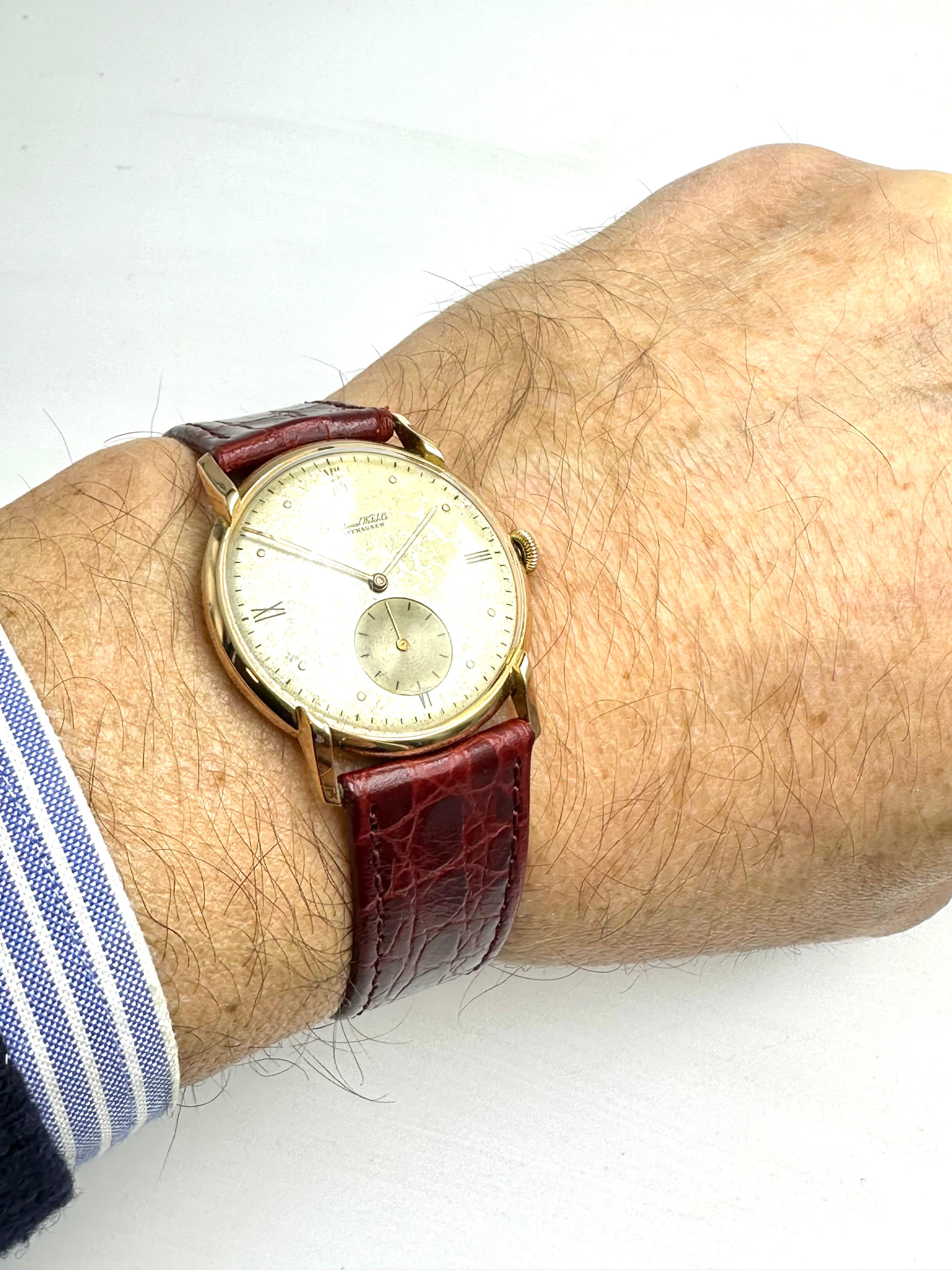 Versetzen Sie sich mit dieser IWC Schaffausen Uhr aus den 1940er Jahren in die Vergangenheit. 
Sie besitzt ein rundes 18-karätiges Goldgehäuse mit einzigartig geformten Bandanstößen, ein silbernes Zifferblatt in ausgezeichnetem Zustand und ein