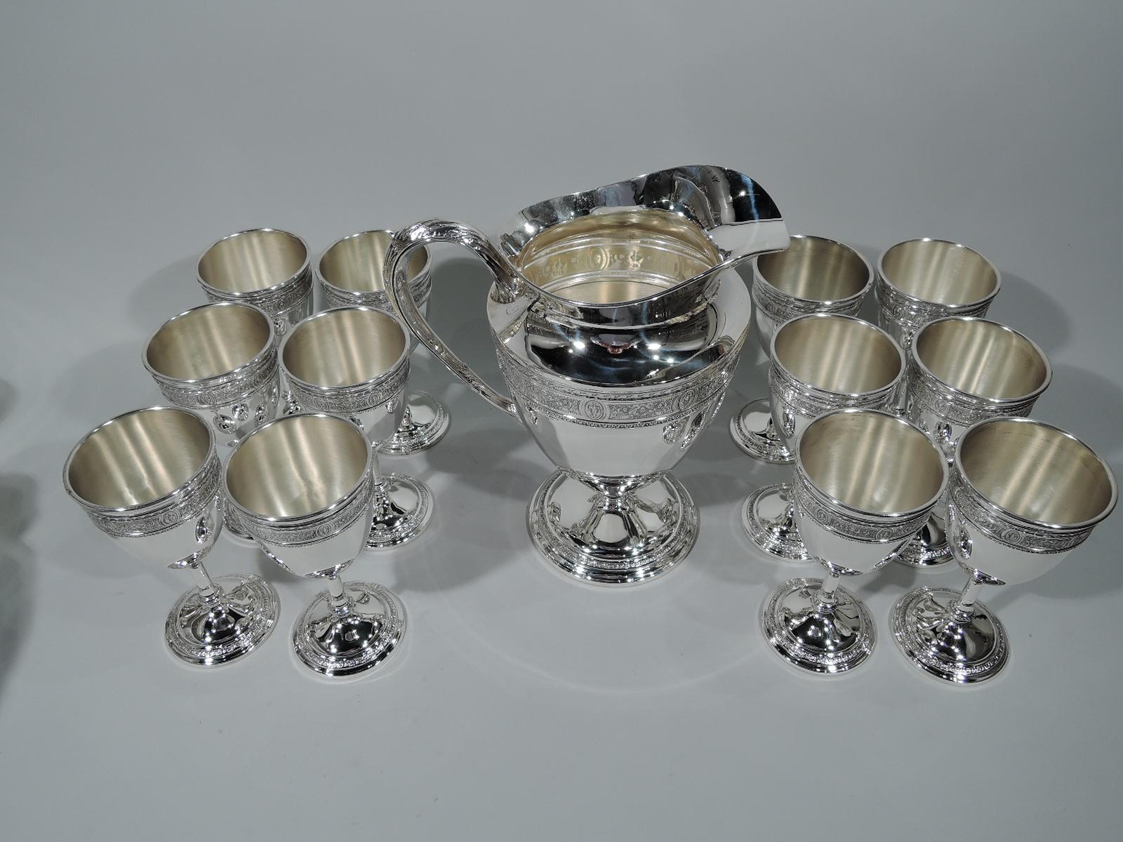 Neoclassical sterling silver drinks set in Wedgwood pattern. Made by International in Meriden, Conn. This set comprises 1 water pitcher and 12 goblets.

Pitcher: Ovoid body, helmet mouth, leaf-capped scroll handle, and stepped foot. Each goblet: