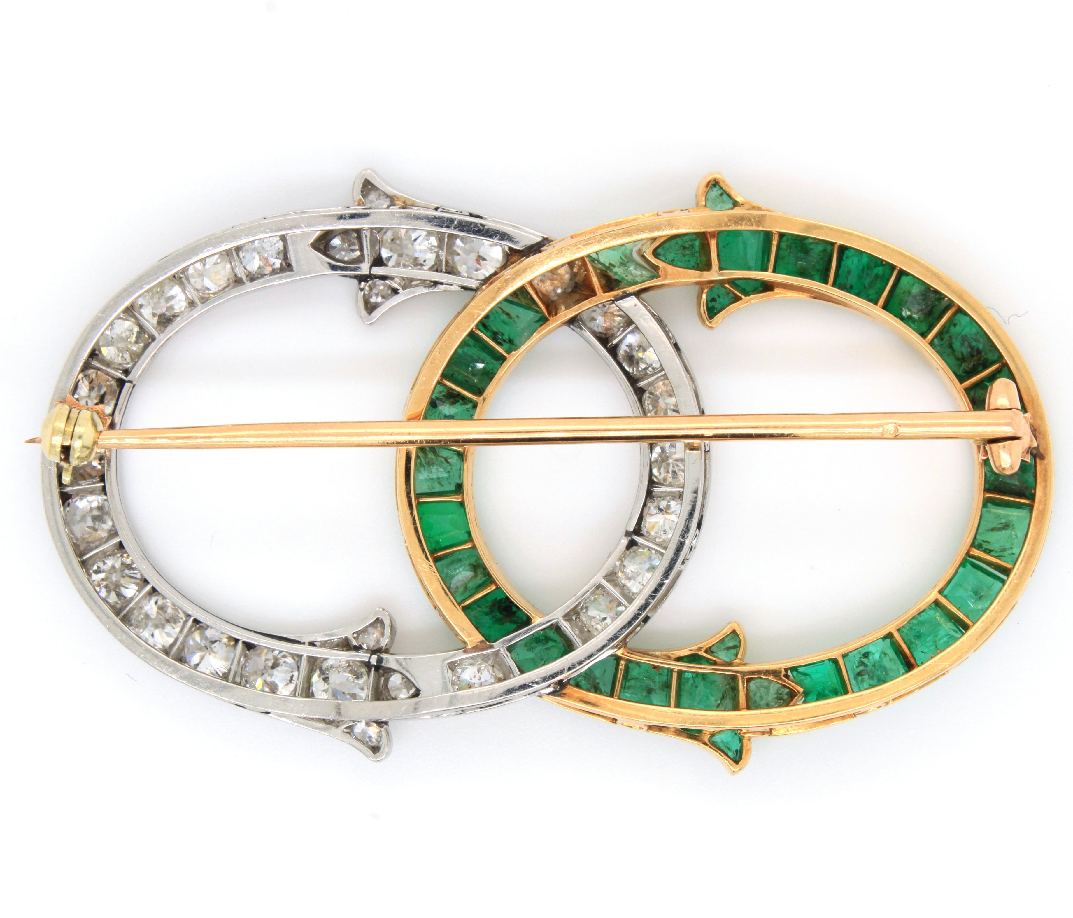 Eine sehr schöne französische Brosche mit Smaragd und Diamanten, von George Fonsèque Art Nouveau, ca. 1910er Jahre. Die Brosche besteht aus zwei ineinander verschlungenen Teilen, die jeweils mit Smaragden im Trapezschliff in Gelbgold und Diamanten