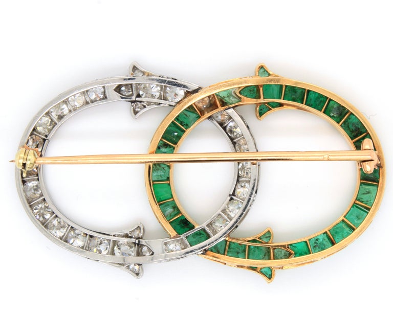 A very beautiful French emerald and diamond brooch, by George Fonsèque Art Nouveau, ca. 1910s. The brooch consists of two intertwining parts, each respective part set with trapeze cut emeralds in yellow gold and old cut diamonds in white gold. The
