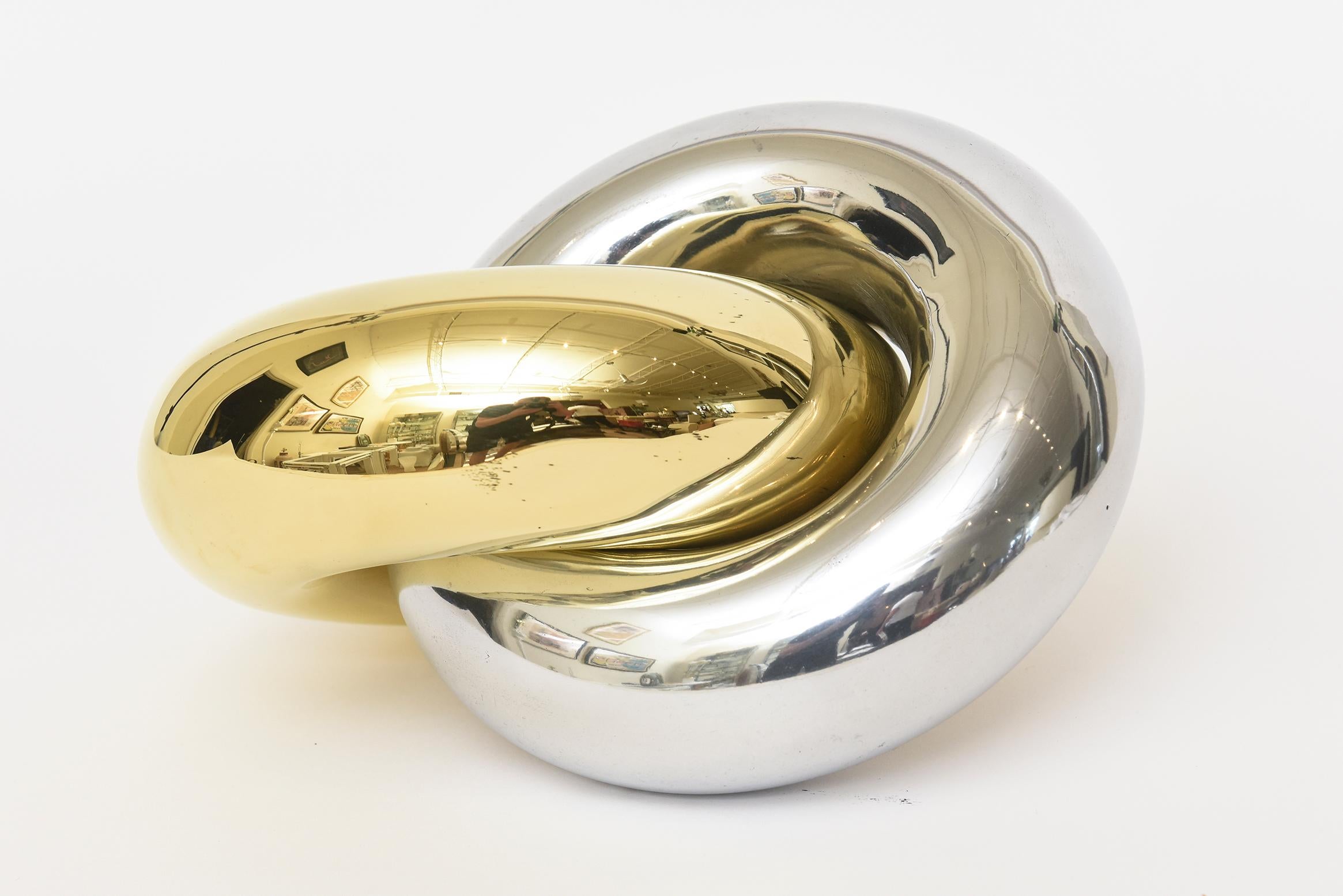 This amazing vintage 1970's intertwined ring sculpture is a duality of brass and chrome plated surfaces that cross over. It has a mirror like effect from all reflections. The two rings are twisted into each other as one great sculpture. it is silver