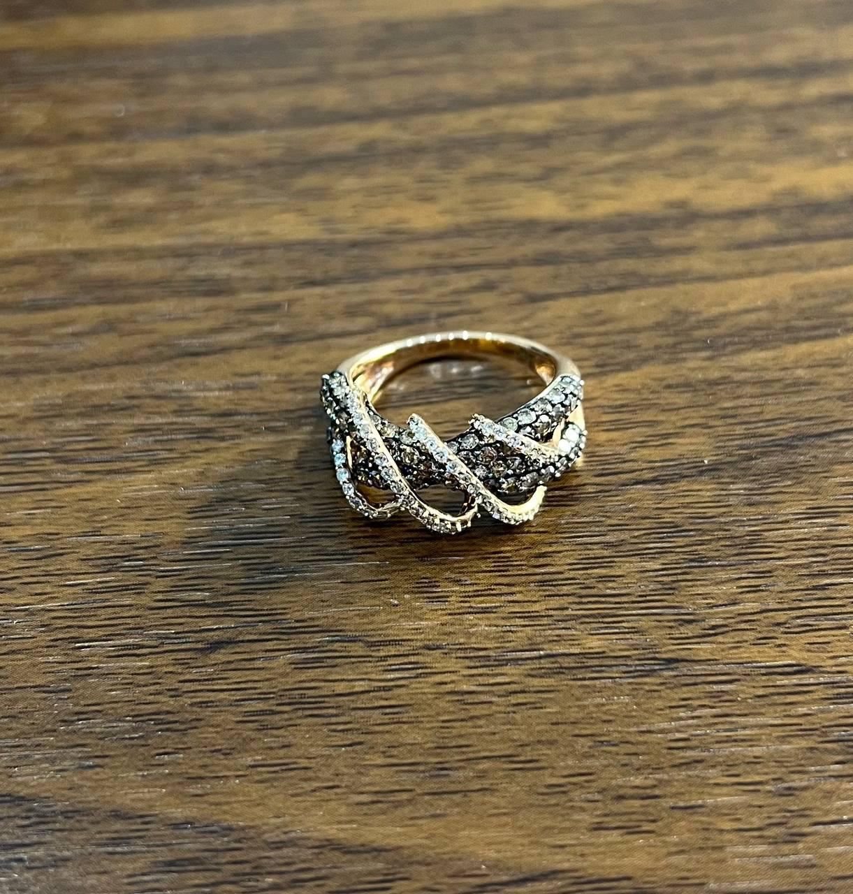 Una sinfonia di curve, texture e brillantezza.

Questo anello di grande effetto presenta un design dinamico con fasce intrecciate incrostate di scintillanti diamanti bianchi e champagne cognac. L'intricato grappolo di pietre crea un accattivante