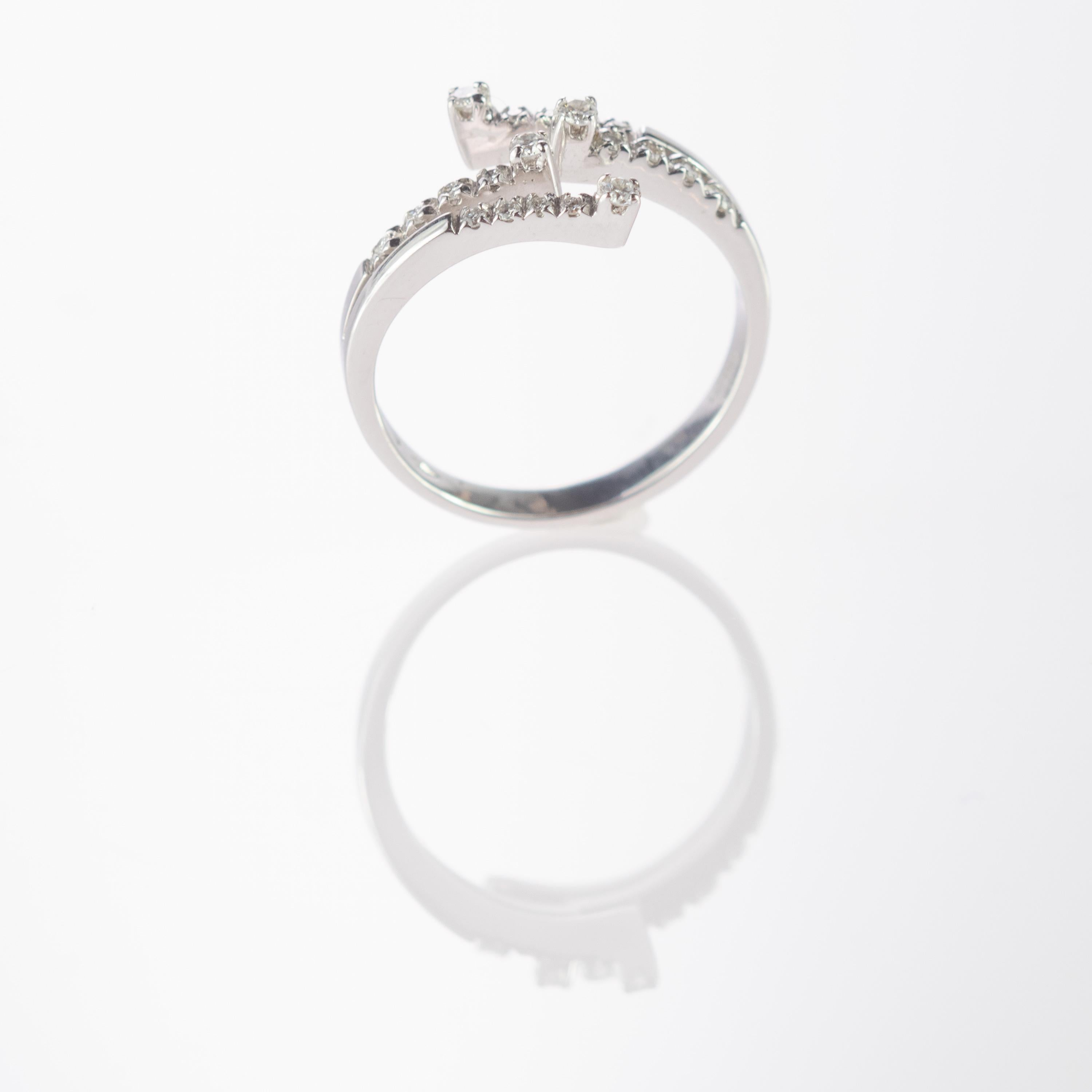 Modern spiral round diamond ring. 0.25 carat diamonds characterized by 20 brilliant precious stones that come together in a delicate shape that sits in a 18 karat white gold bypass form. A Legacy, feminine and breathtaking ring mirroring a retro