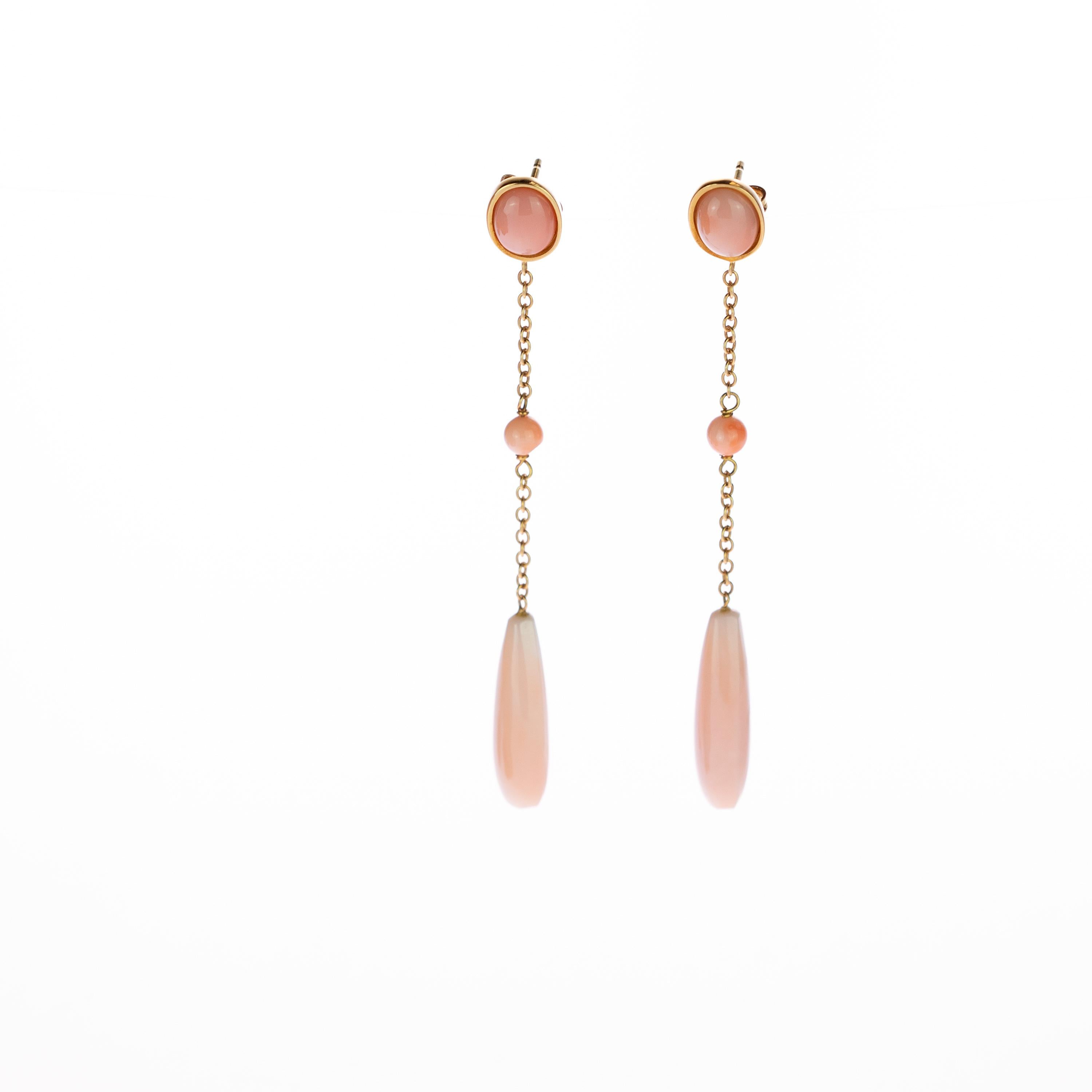 Colossal and extraordinary dangle drop earrings modeled in different shapes by pink carved coral embellished with 18 karat yellow gold. A delicate chain that connects an oval cabochon, a round donut and a bold tear or briolette that melted