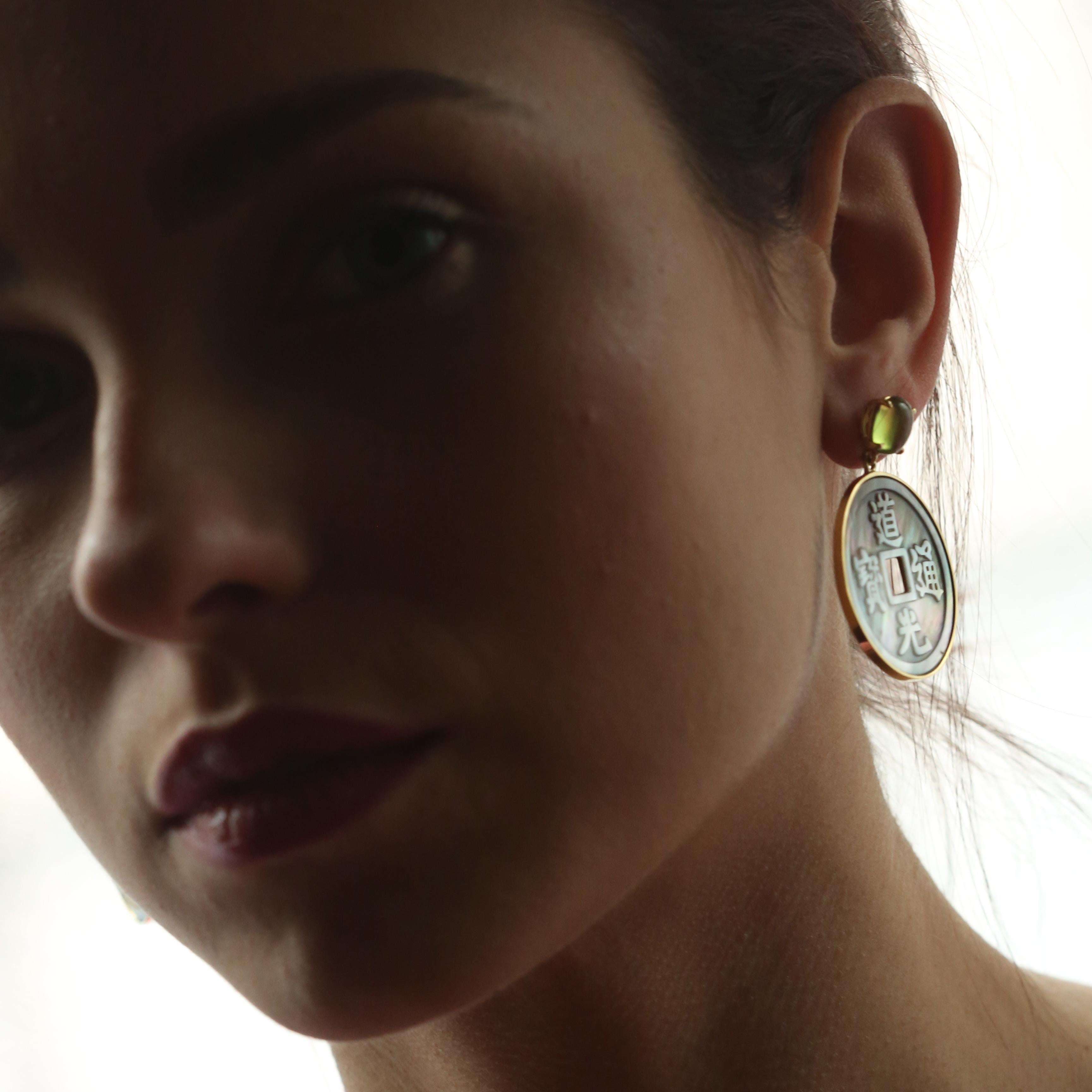 Pendientes artesanales de gota de peridoto ovalado verde engastados en oro de 18 quilates que sujetan un diseño de donut de nácar redondo perfectamente elaborado. Los símbolos chinos del amor, la sabiduría, el éxito y la esperanza quedan realzados