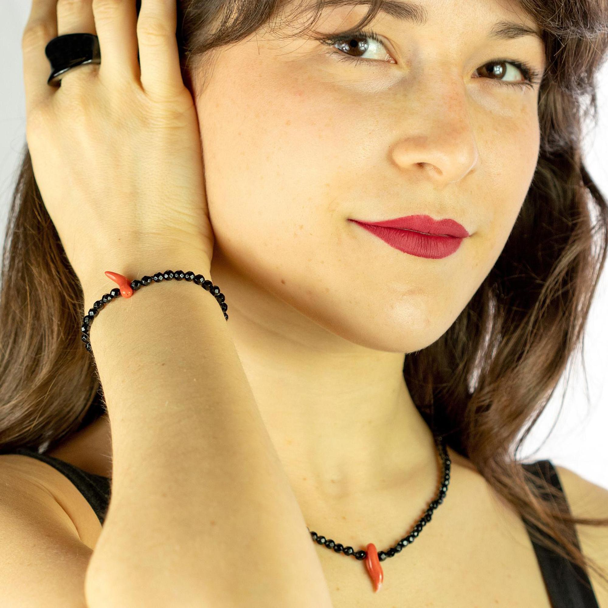 Una pulsera ligera, ideal para el uso diario, de ágata negra facetada con un colgante central de cuerno de coral rojo. Sumérgete en la belleza de esta pulsera de diseño único con piedras naturales llenas de vida y color. Una joya de inspiración