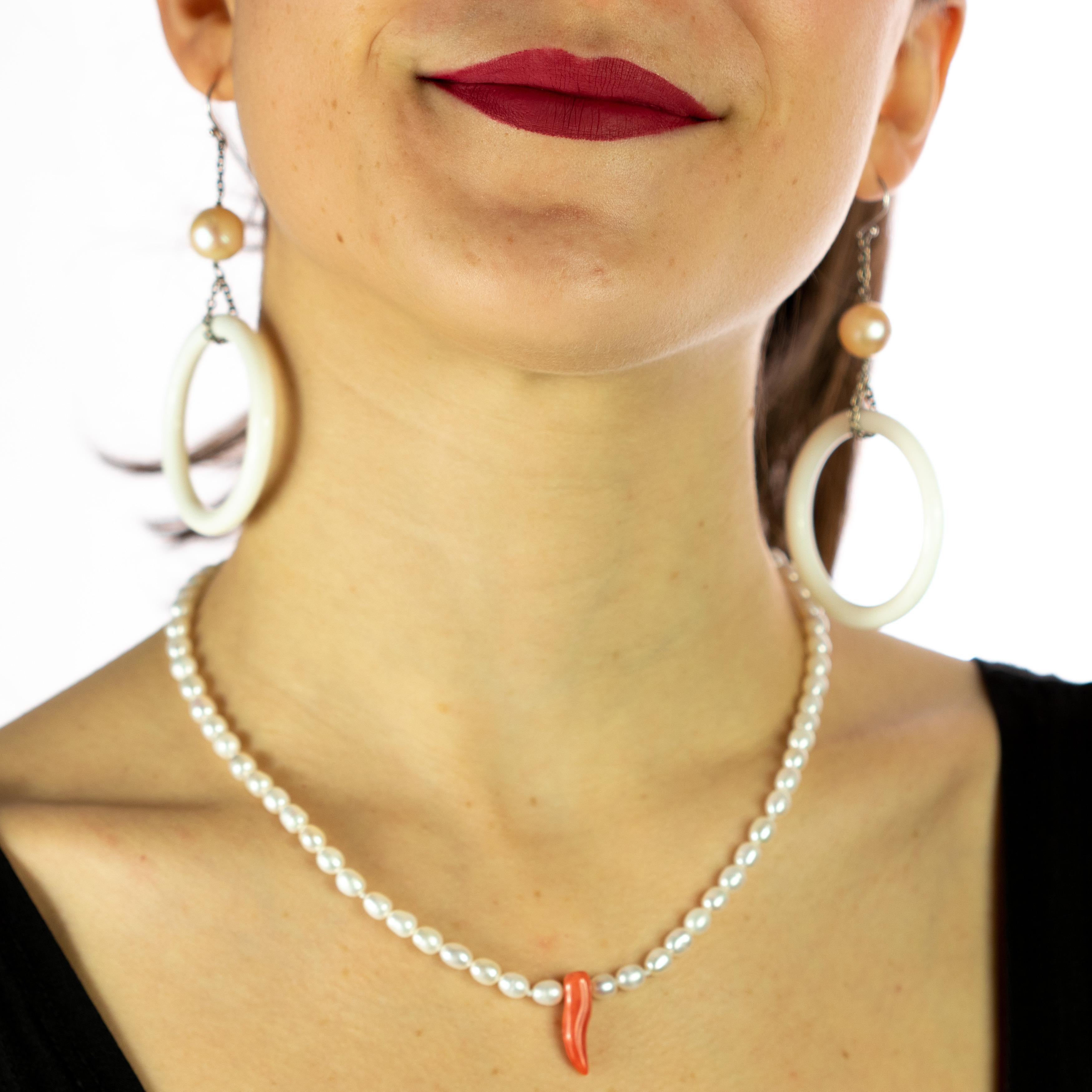 An elegant and light weighted freshwater pearl necklace with a unique design with a central pendant in red coral. Immerse yourself in the beauty of this uniquely designed jewel with natural stones full of life and color. A handmade hawaiian