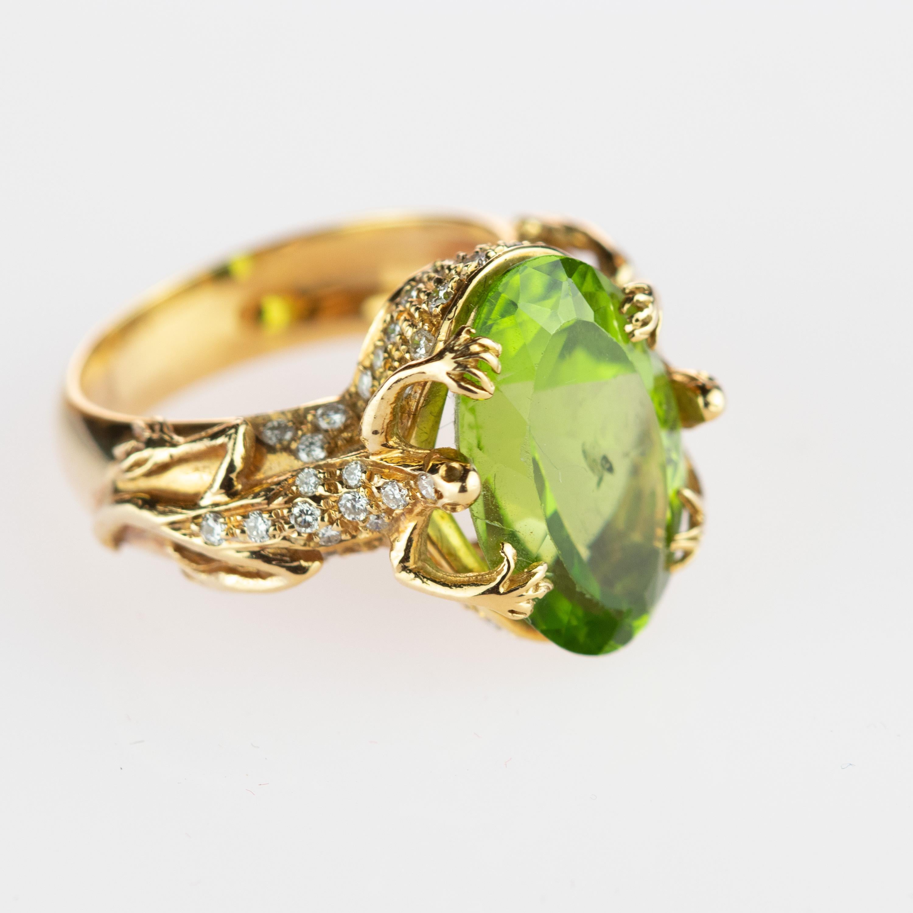An impressive clear natural Peridot 8.8 carat gemstone surrounded on each side by mystic salamanders. Like in a natural throne the animals are composed by 0.7 carat diamonds and surrounded by 18 karat yellow gold. This epic statement ring is an