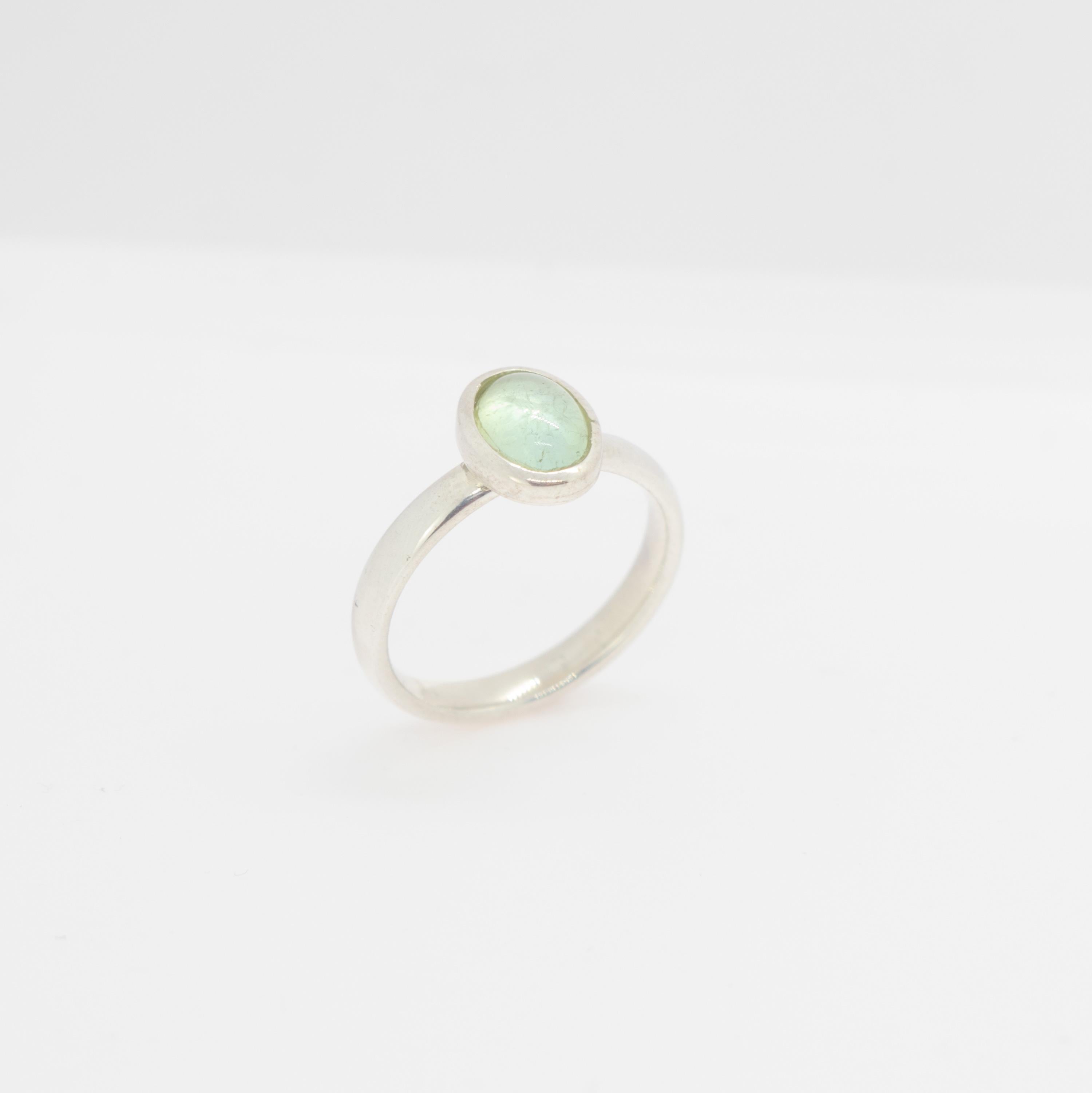 Light green tourmaline gemstone with an oval cabochon design embellished in a sterling silver ring. This gem will fill your daily elegant outfits with a modern and simple design. The light  green tourmaline ​​represents the stone of hope and